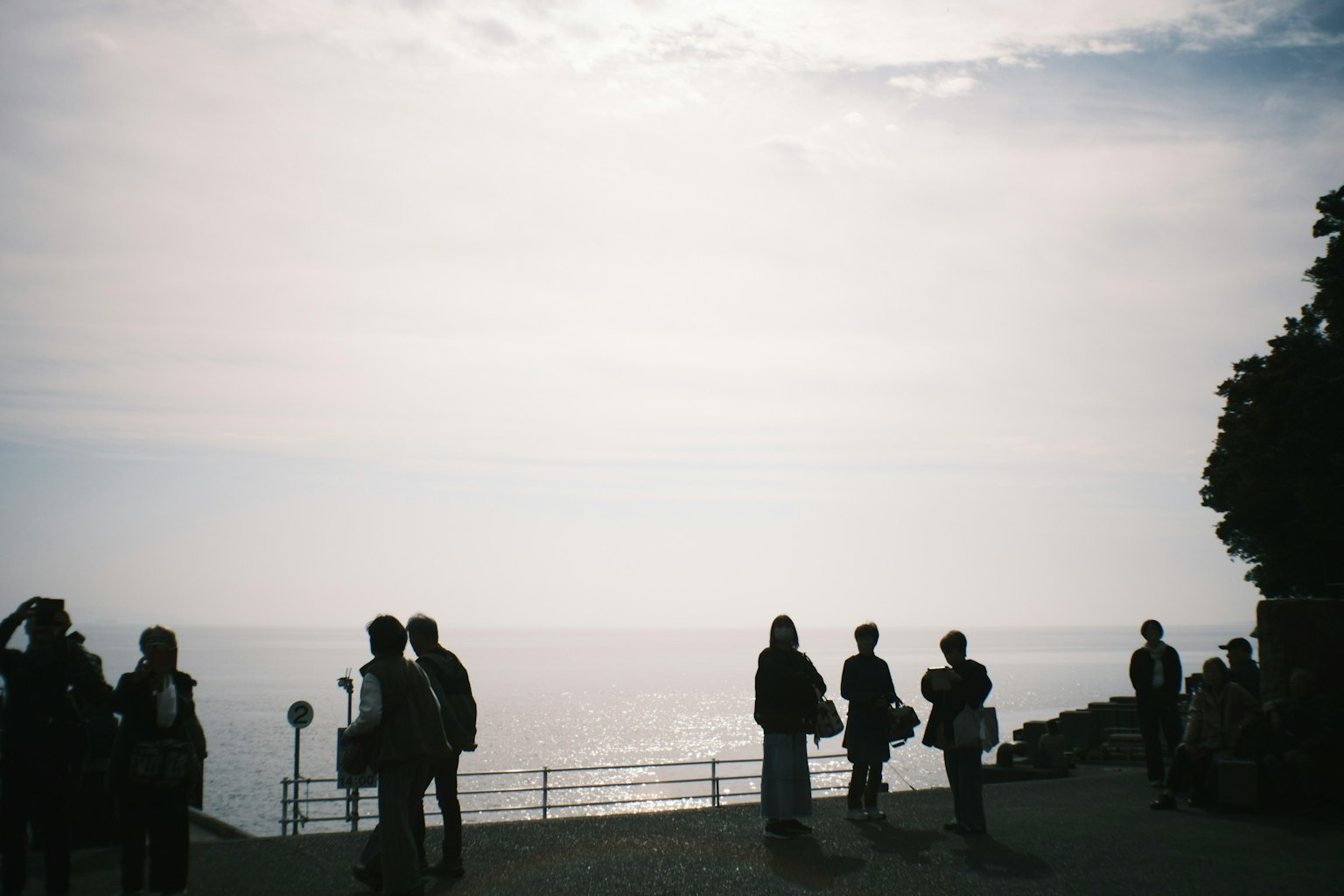 海を背景にしたシルエットの人々が立っている風景