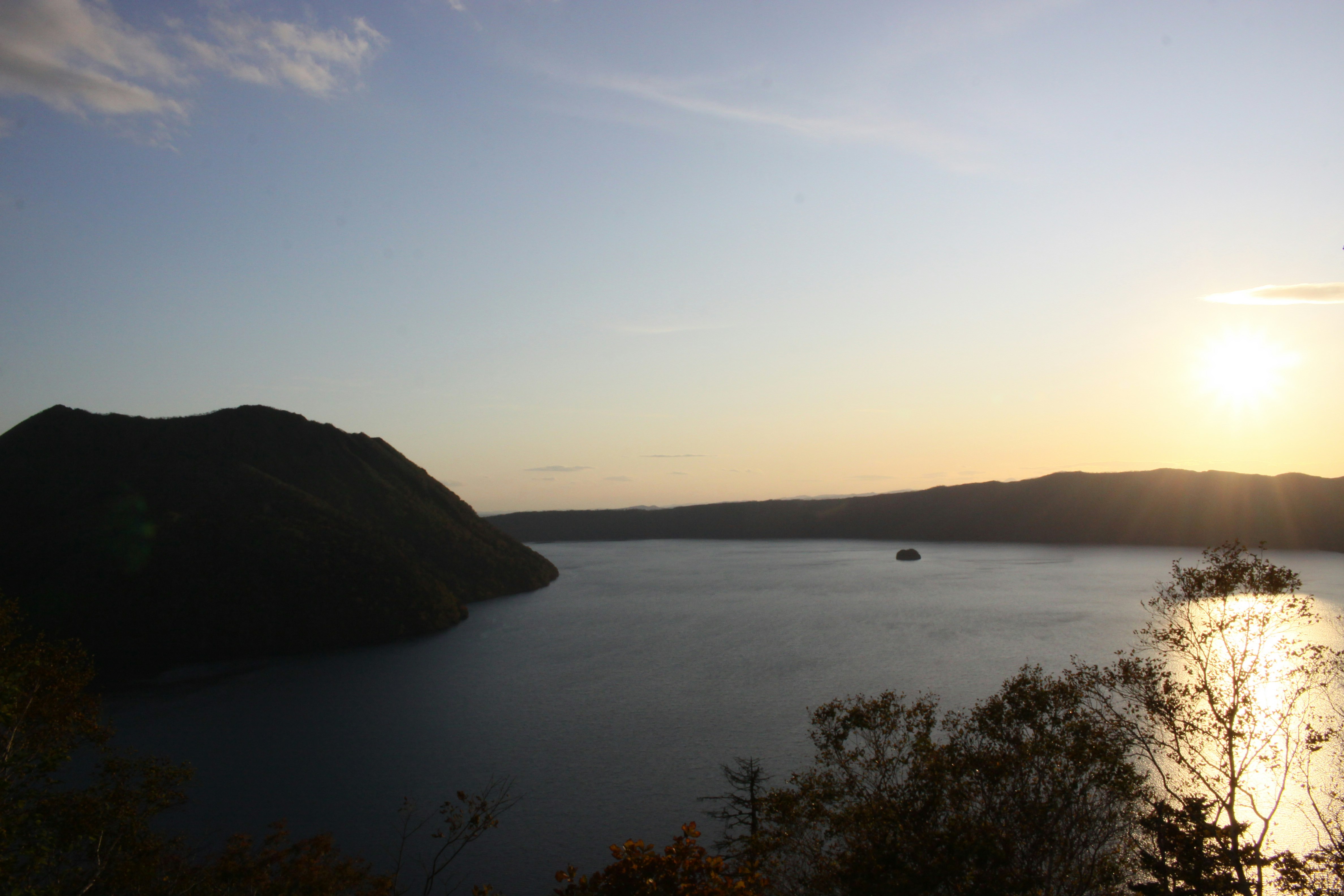 夕日に照らされる湾と山並みの風景