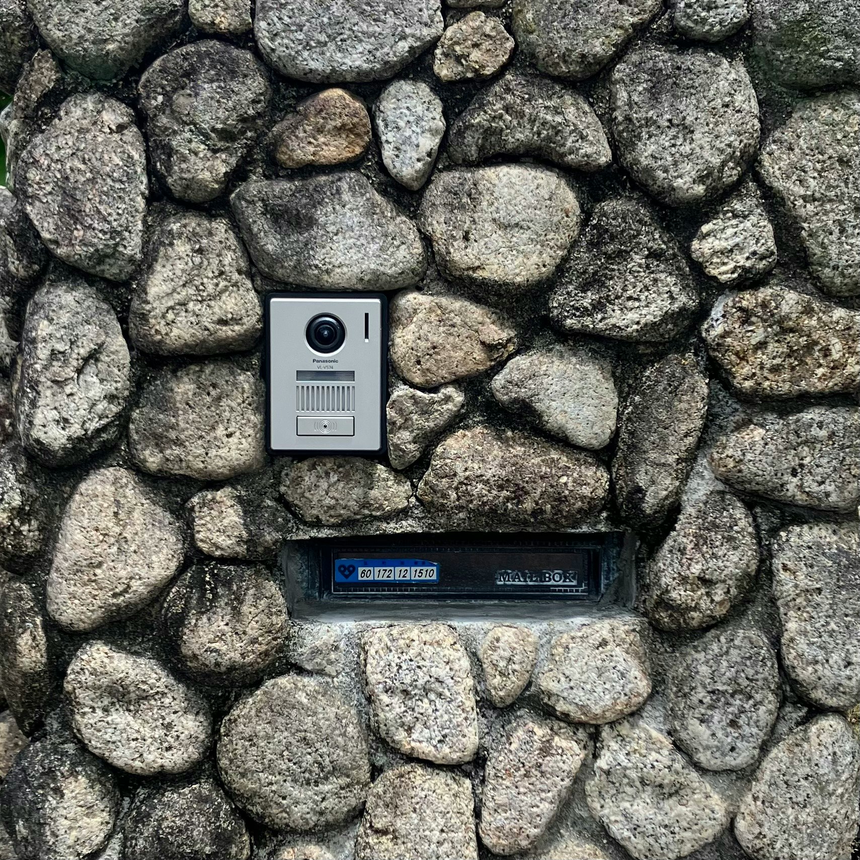 Gegensprechanlage und Namensschild an einer Steinmauer