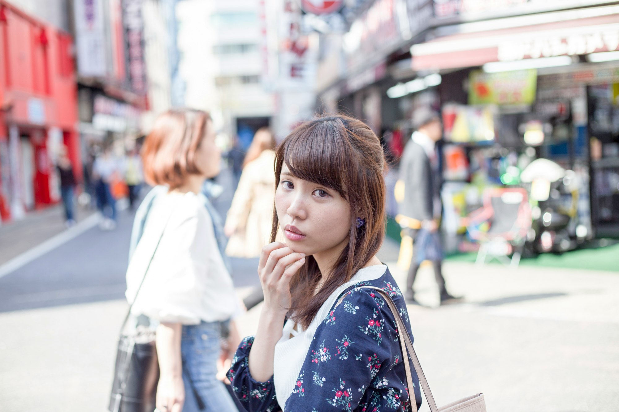 商店街小巷里托着下巴的女性