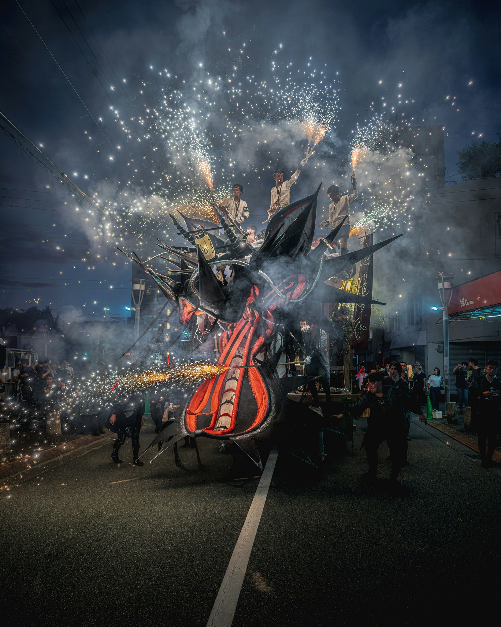 火花が舞う大きな山車と祭りの群衆の通り