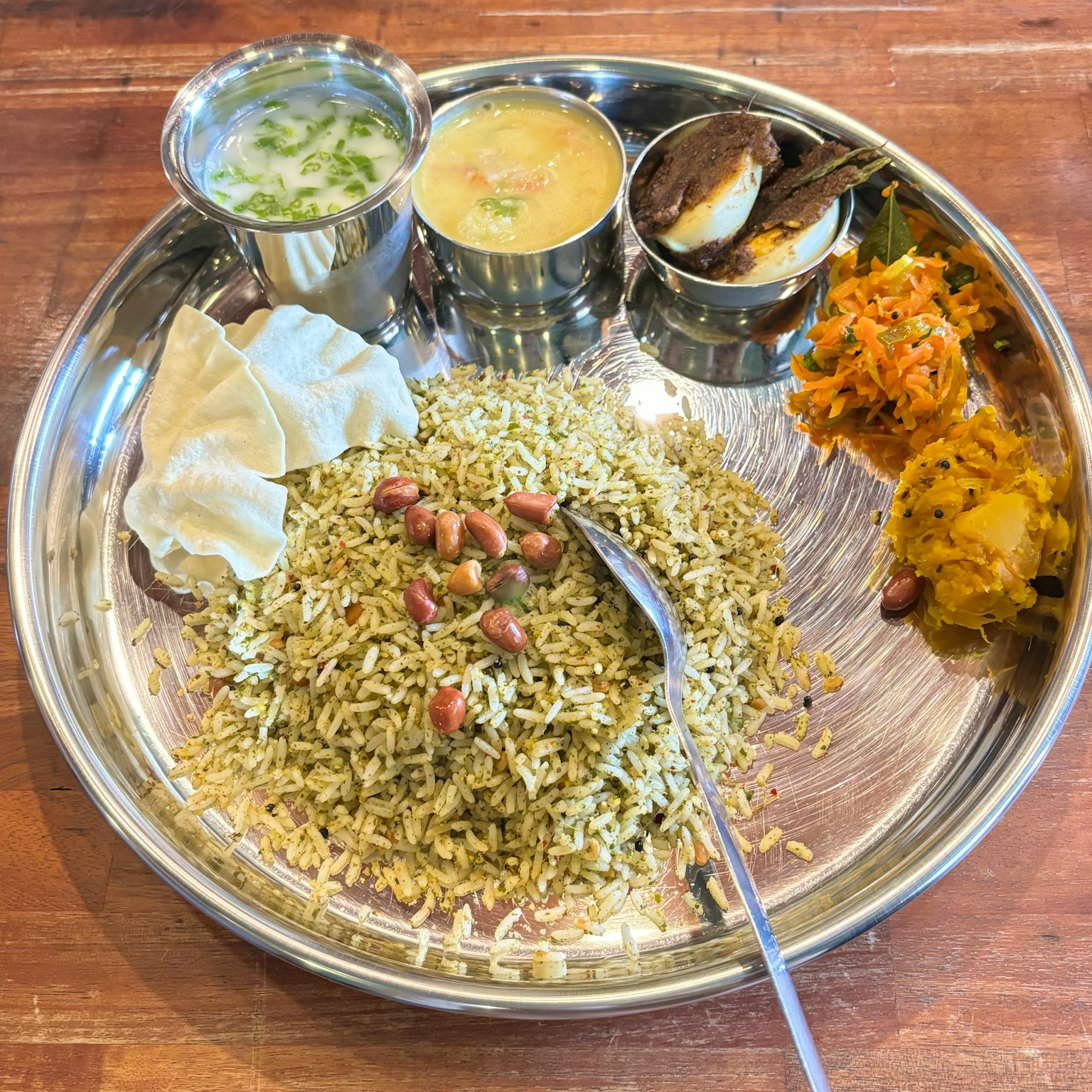 Piring perak yang penuh dengan masakan India dengan nasi dan hidangan sampingan