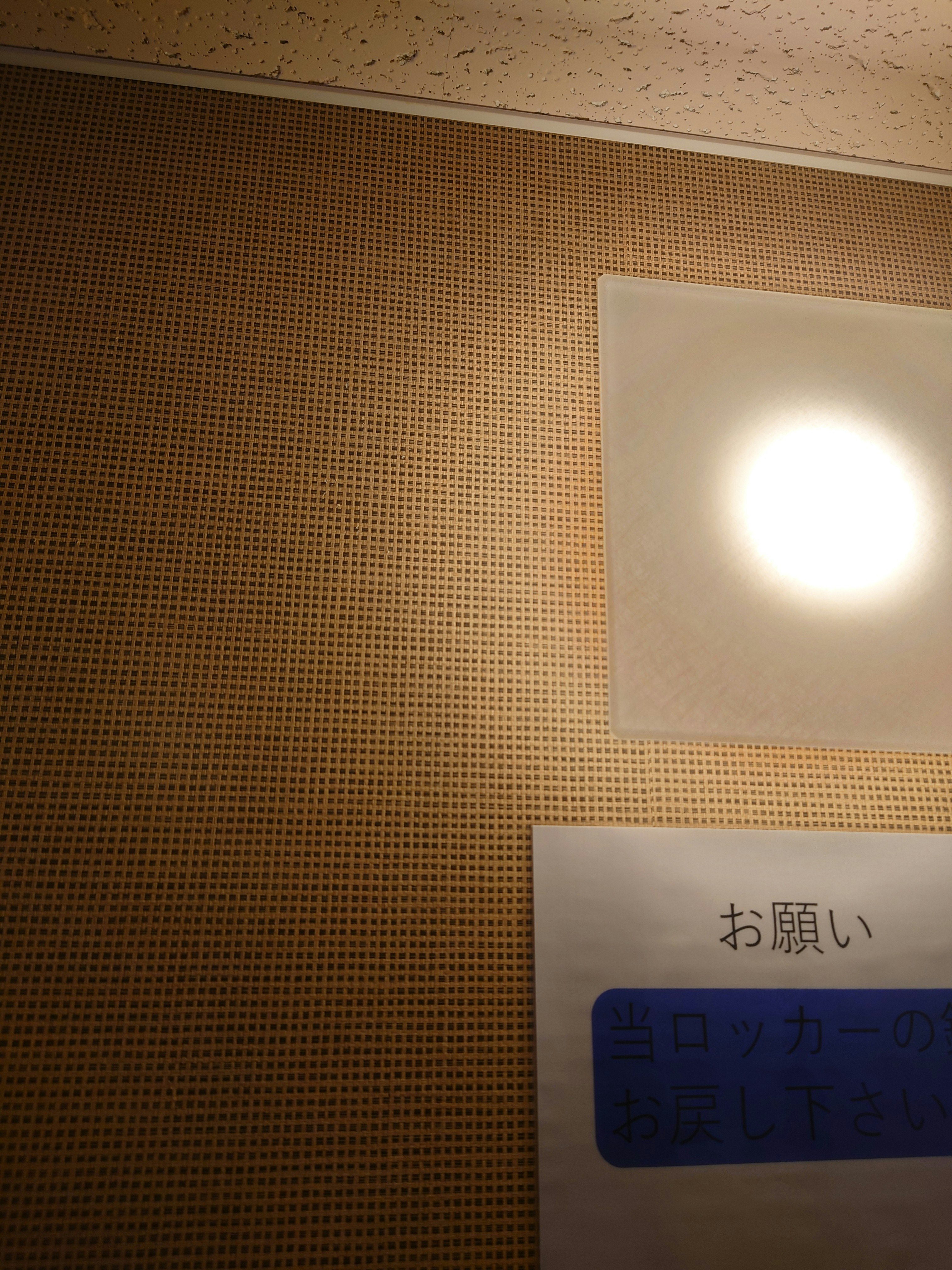 ベージュの壁に貼られた掲示板と案内サインのある室内空間