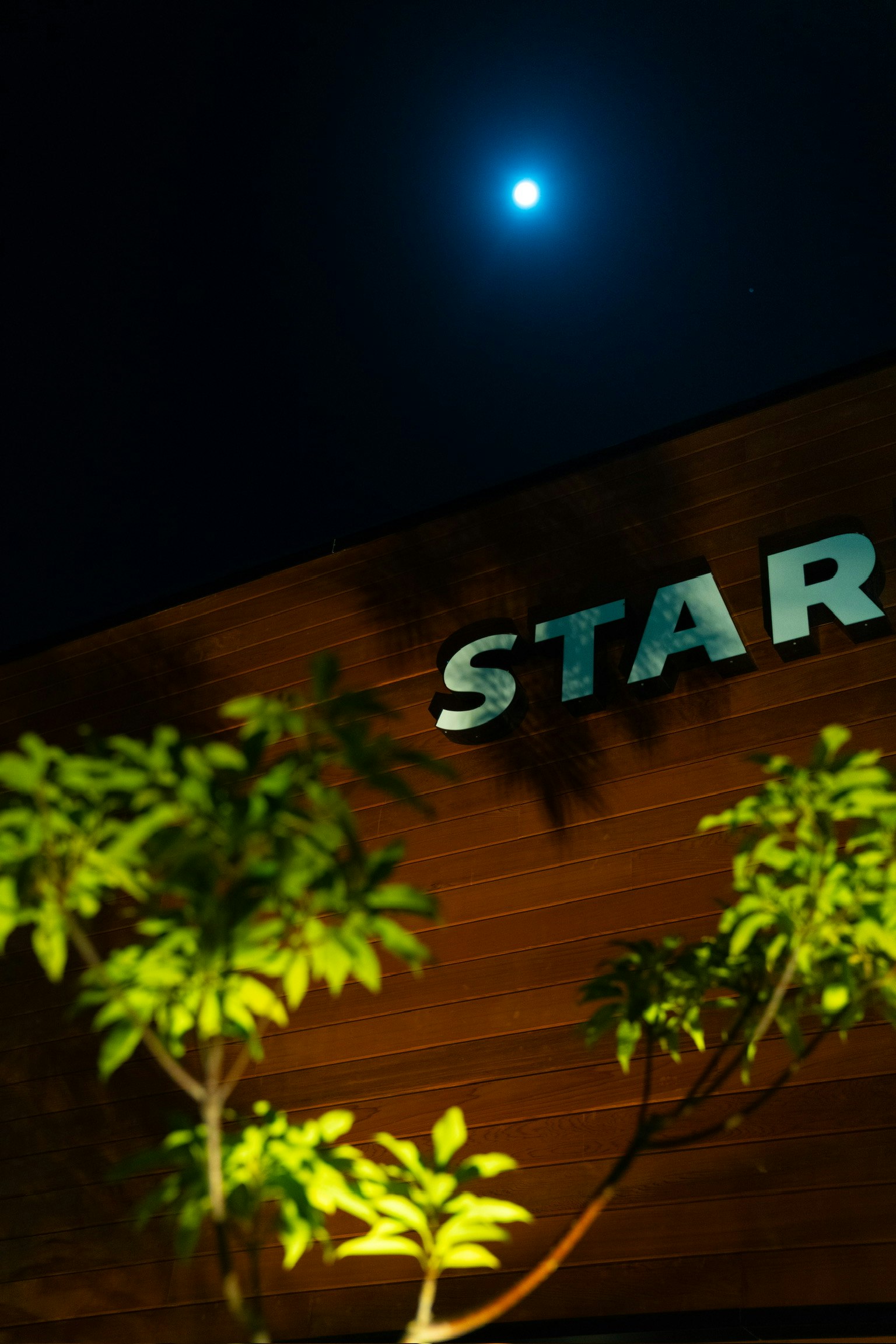 夜空に輝く月と「STAR」の看板が見える風景