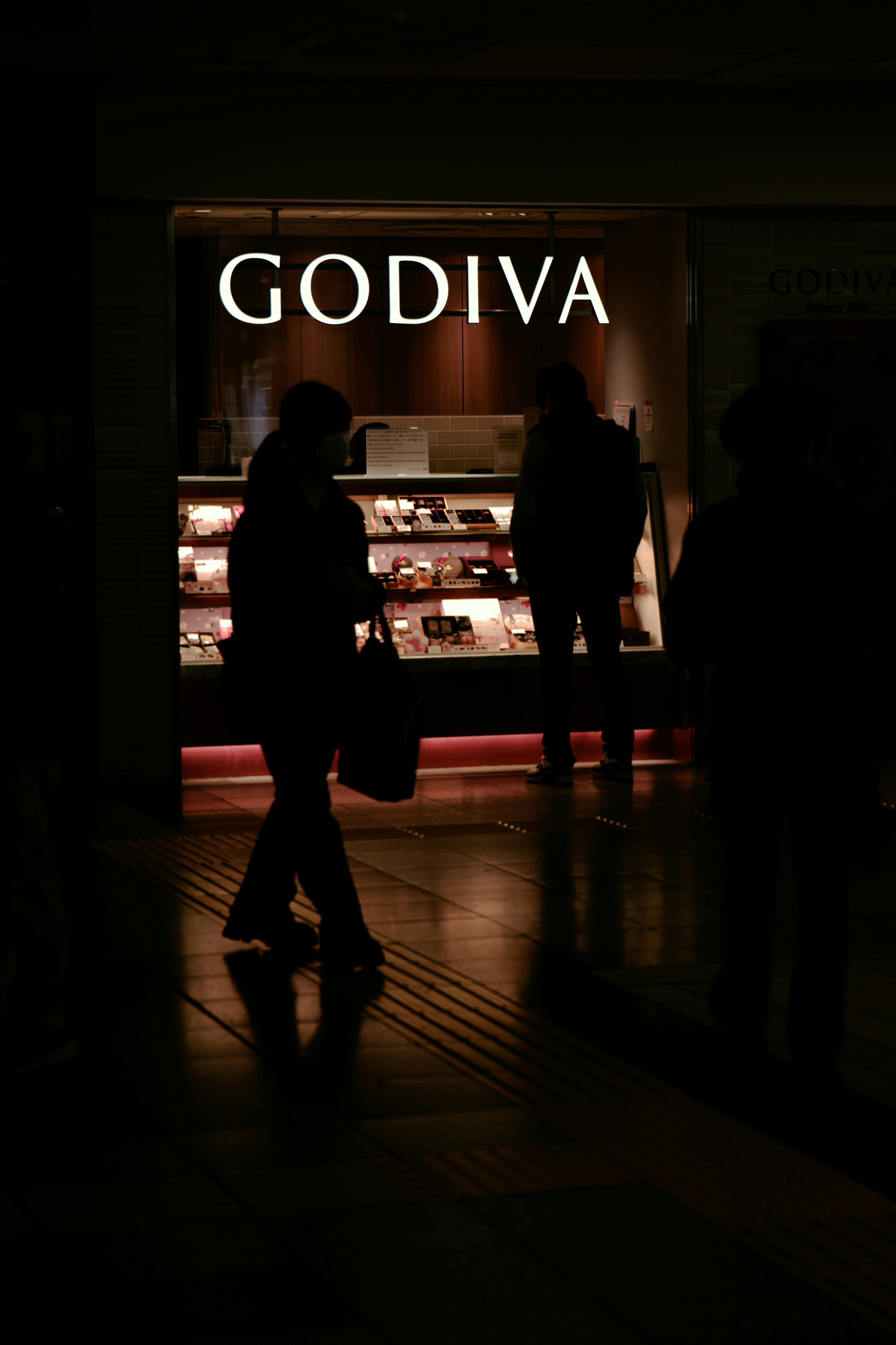 GODIVA 매장 진열대 앞 야경 실루엣 인물