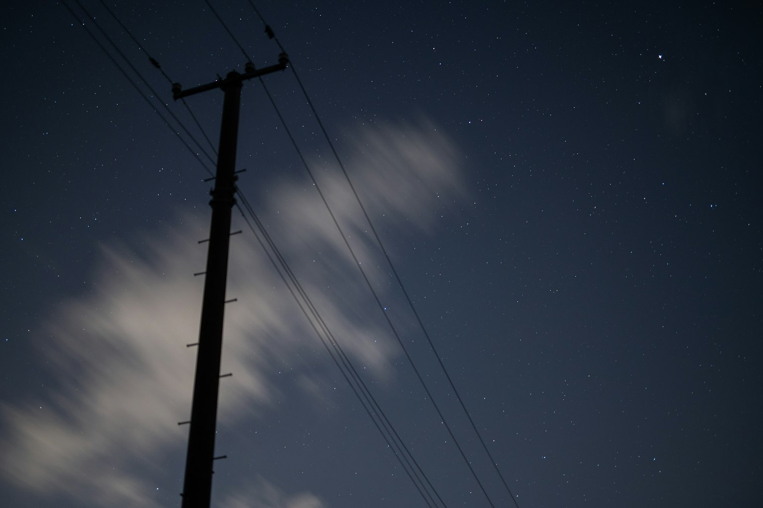 夜空に立つ電柱と星々を背景にした風景