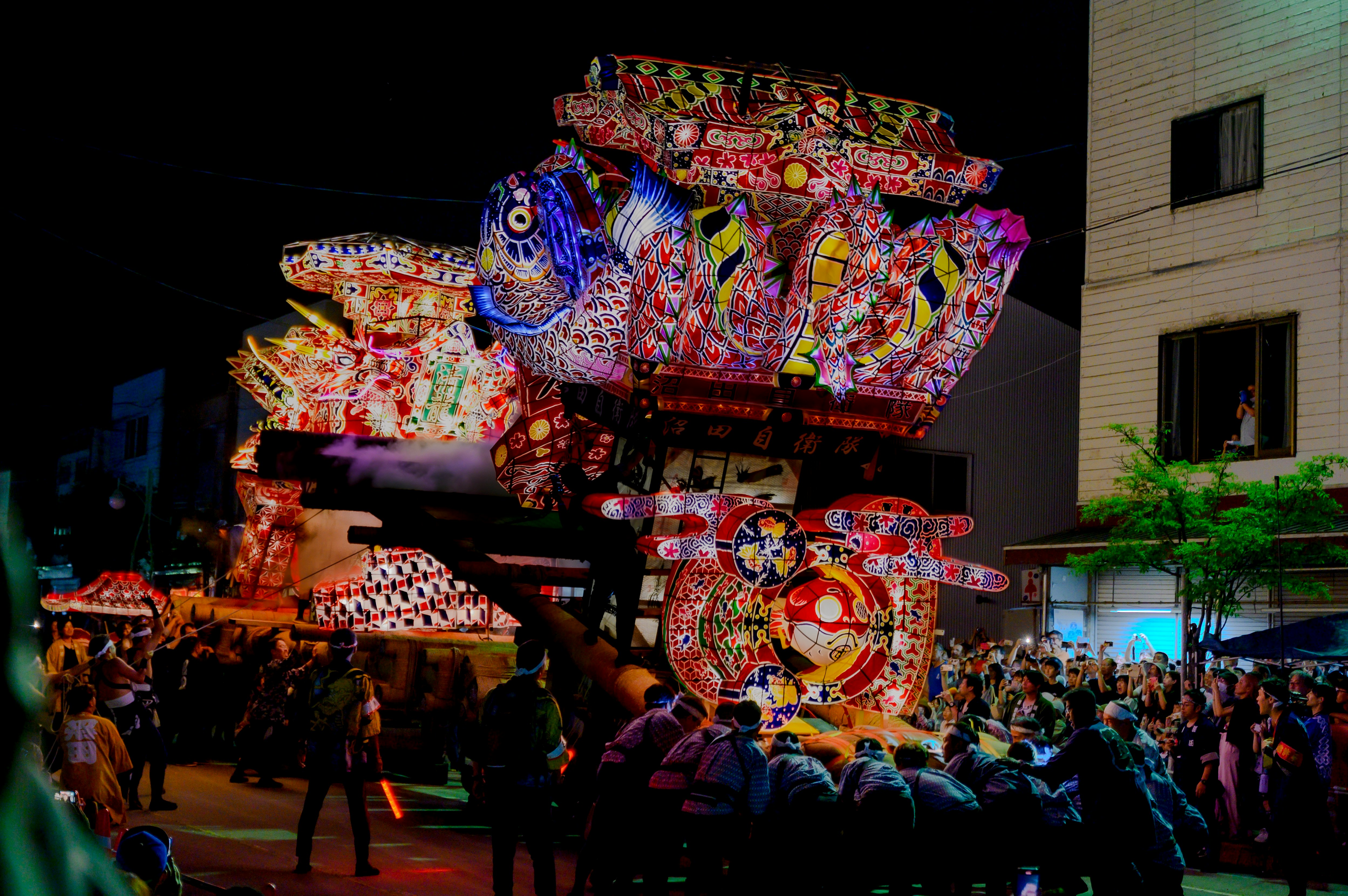 夜の街で大きな山車が練り歩く祭りの光景