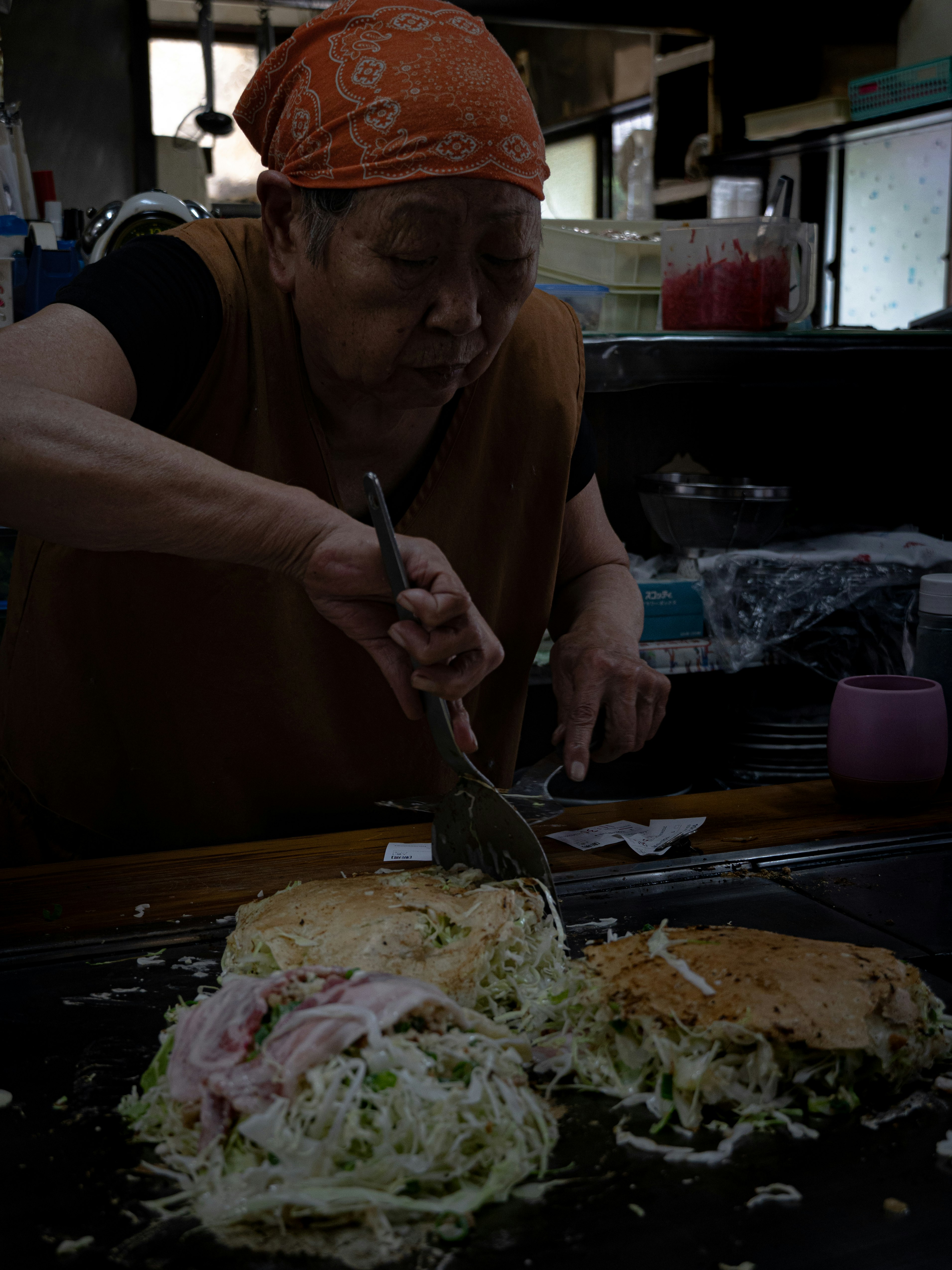 tangan koki memasak okonomiyaki di atas teppan