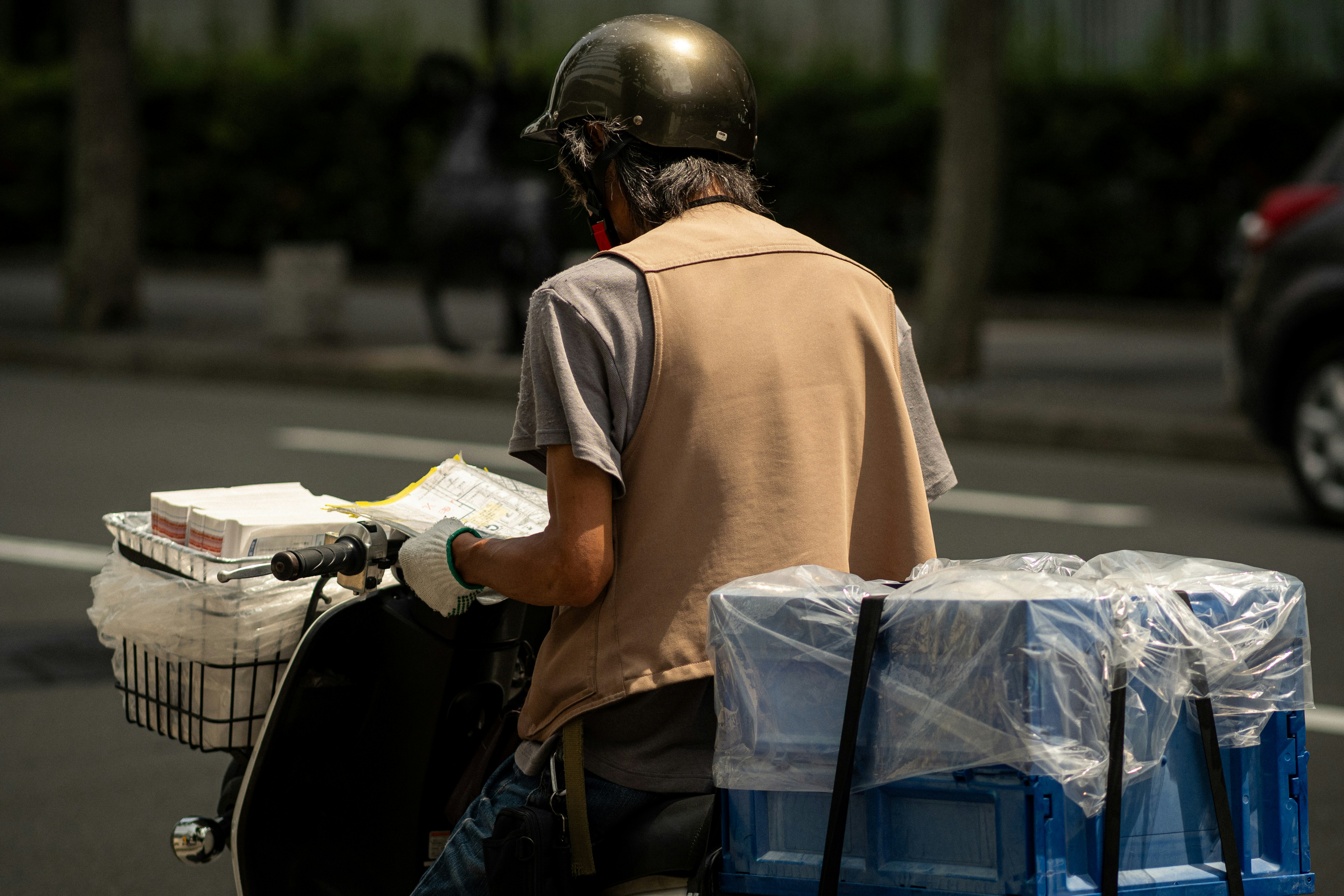 路上で配達用の荷物を運ぶ働く人の後ろ姿