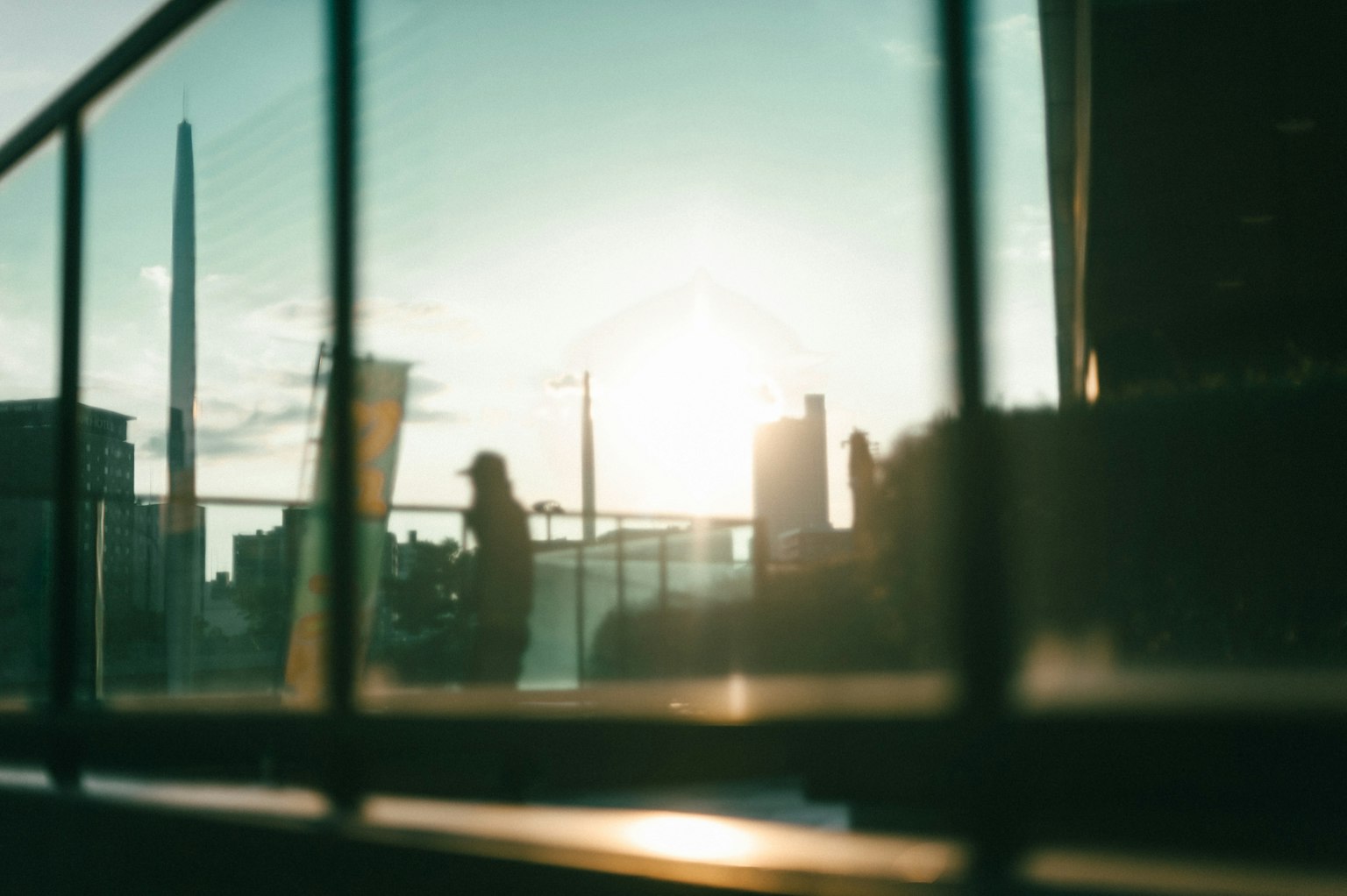 Silueta de una ciudad con fondo de atardecer enmarcada por una rejilla metálica