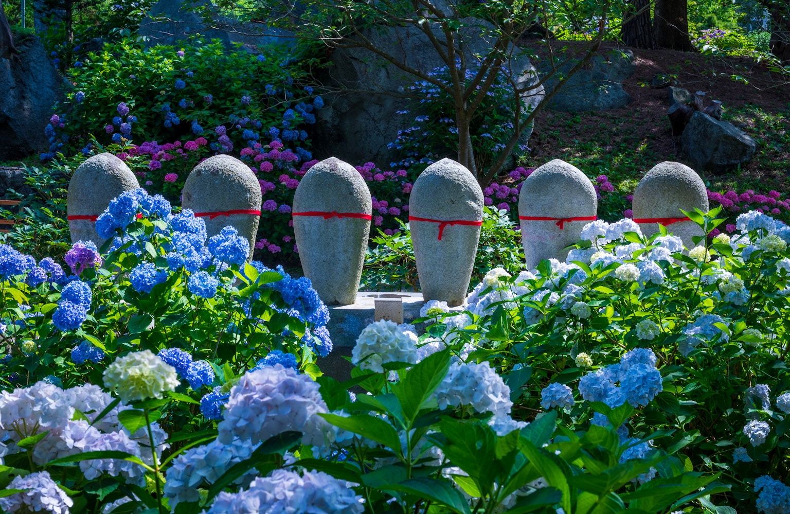 Un gruppo di sculture in pietra circondate da ortensie blu