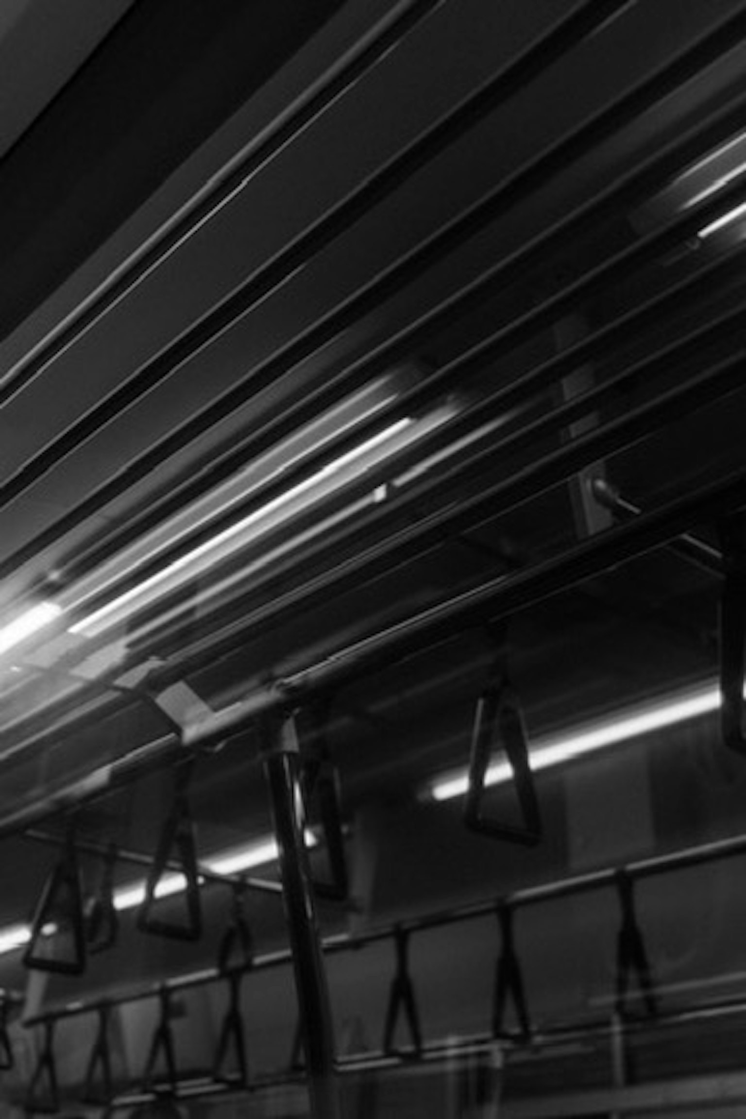 Intérieur d'un train de métro en noir et blanc avec des sangles suspendues