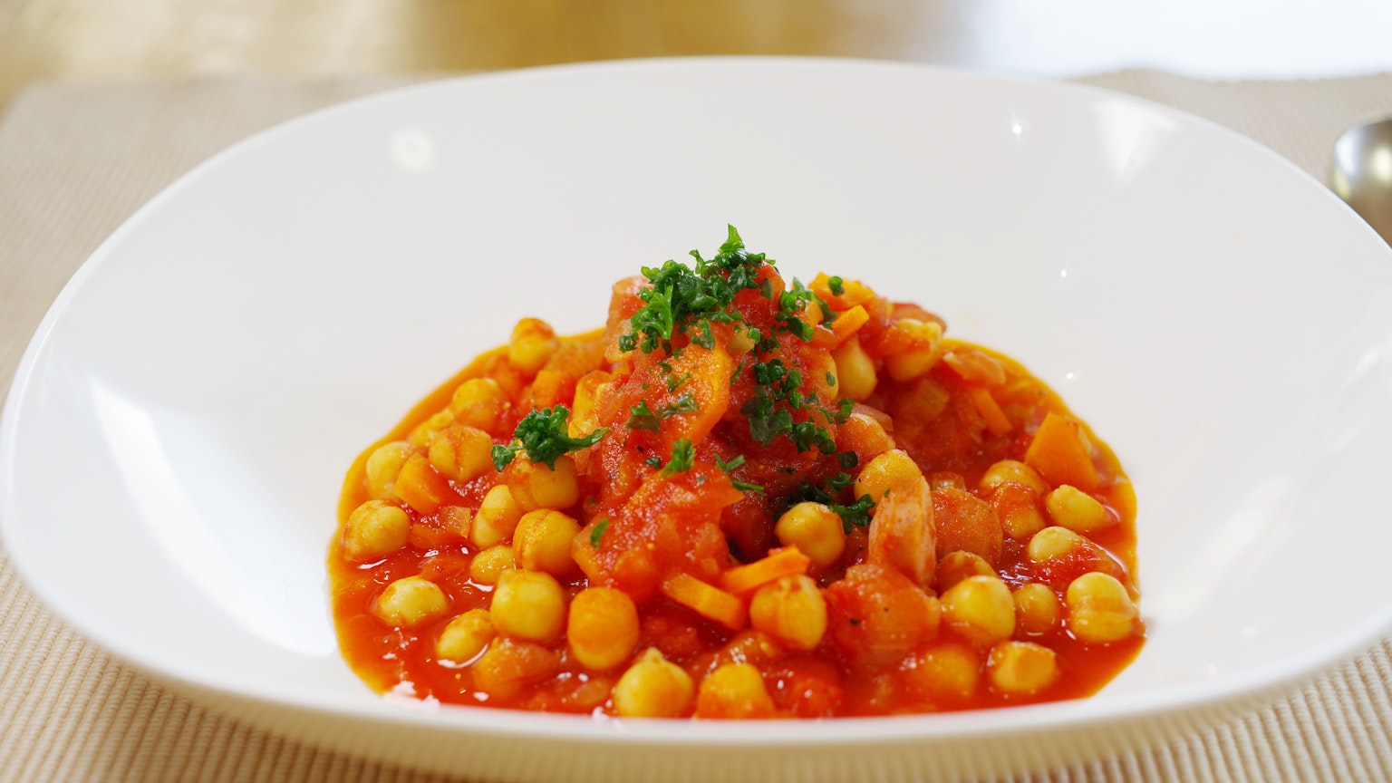 Kichererbsengericht in Tomatensauce mit Petersilie auf einem weißen Teller