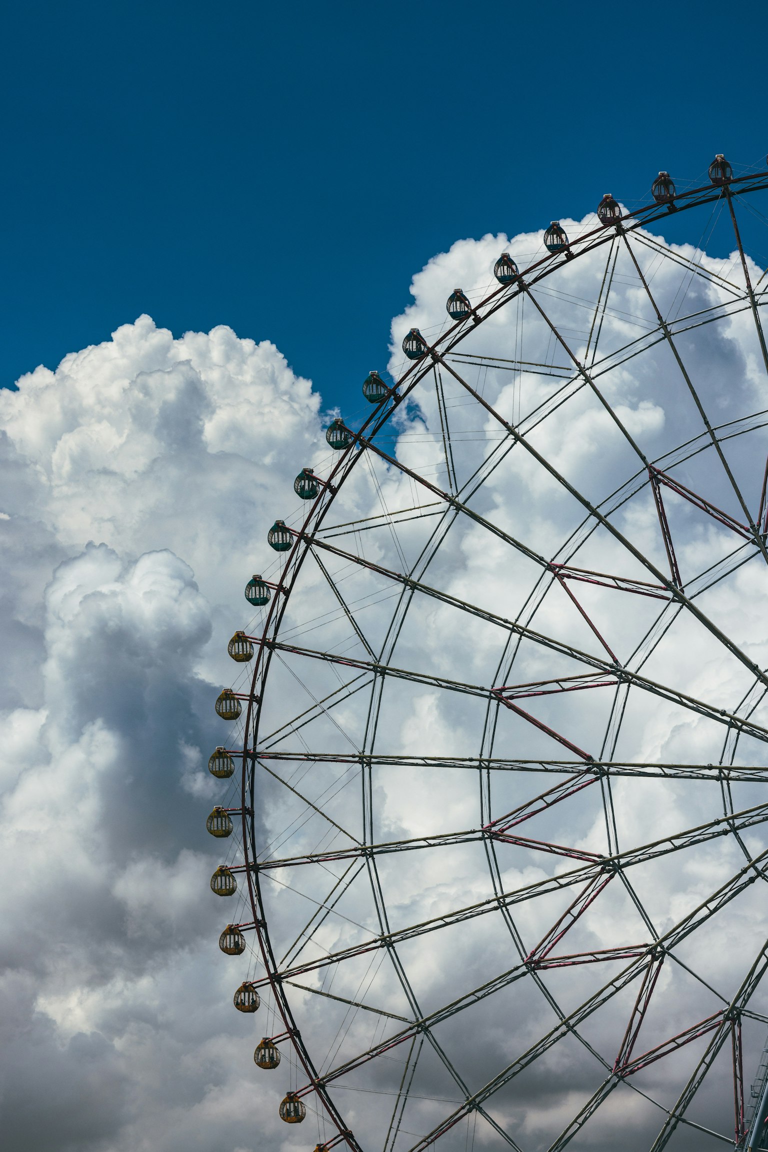 Grande ruota panoramica contro un cielo blu con nuvole bianche soffici