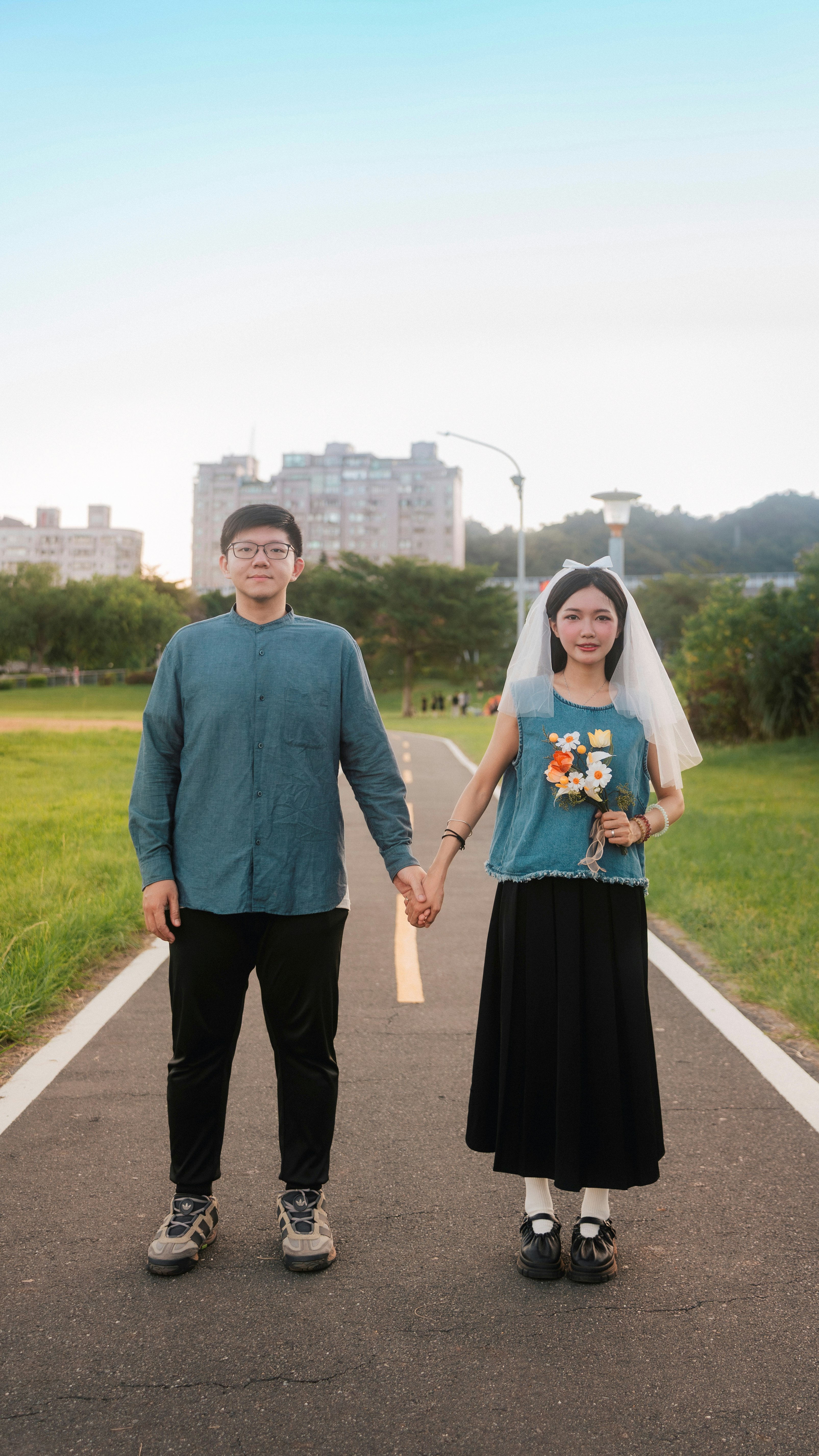 草地の遊歩道を歩く新郎新婦のカップル