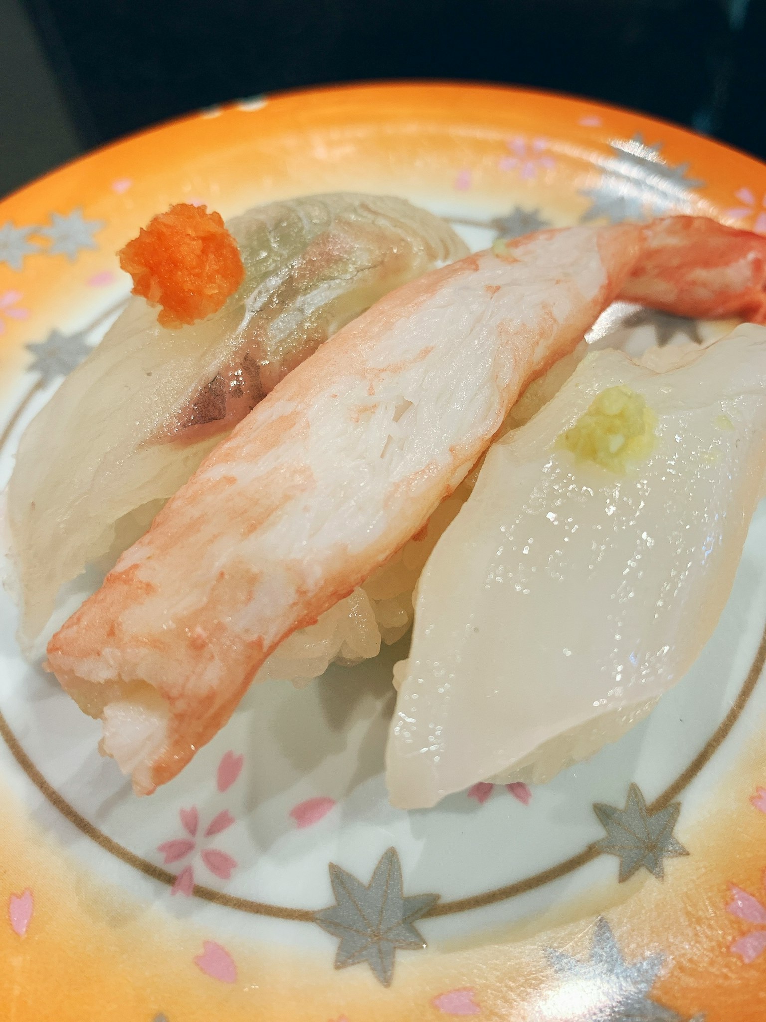 多样寿司，包括虾、蟹、白鱼，呈现在色彩鲜艳的盘子上