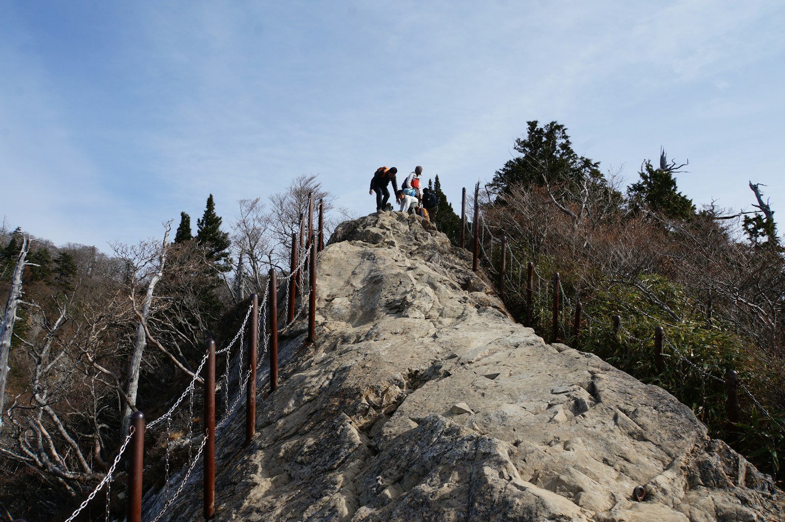 Randonneurs grimpant une montagne rocheuse sous un ciel bleu