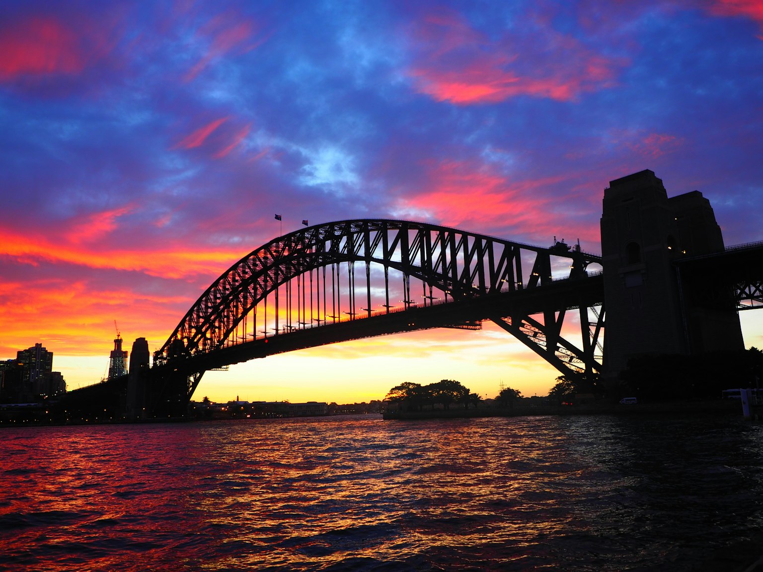 Sydney Harbour Bridge silhouetted against a vibrant sunset