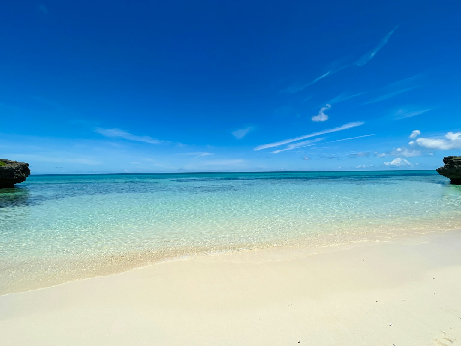 ชายหาดที่มีน้ำใสและท้องฟ้าสีฟ้า ทรายและชายฝั่งหิน