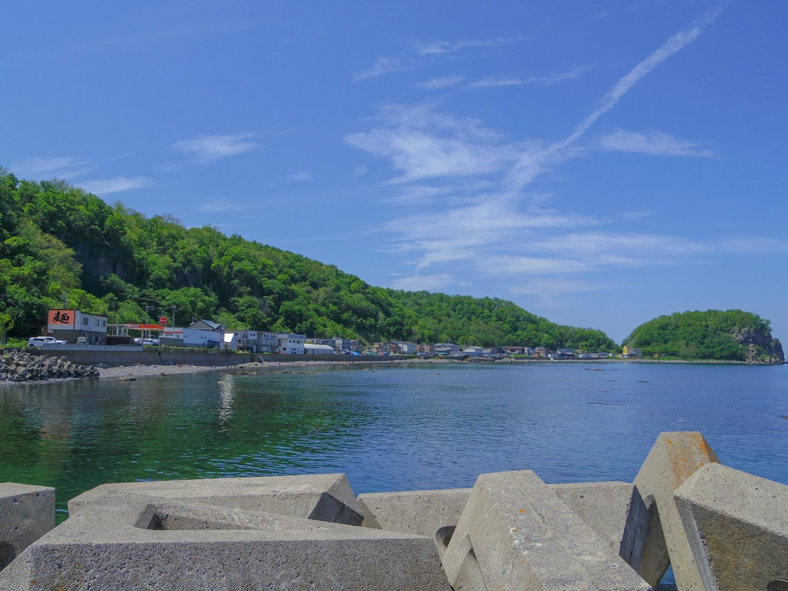 Malersicher Blick auf das ruhige Meer und die üppigen Hügel unter einem klaren blauen Himmel