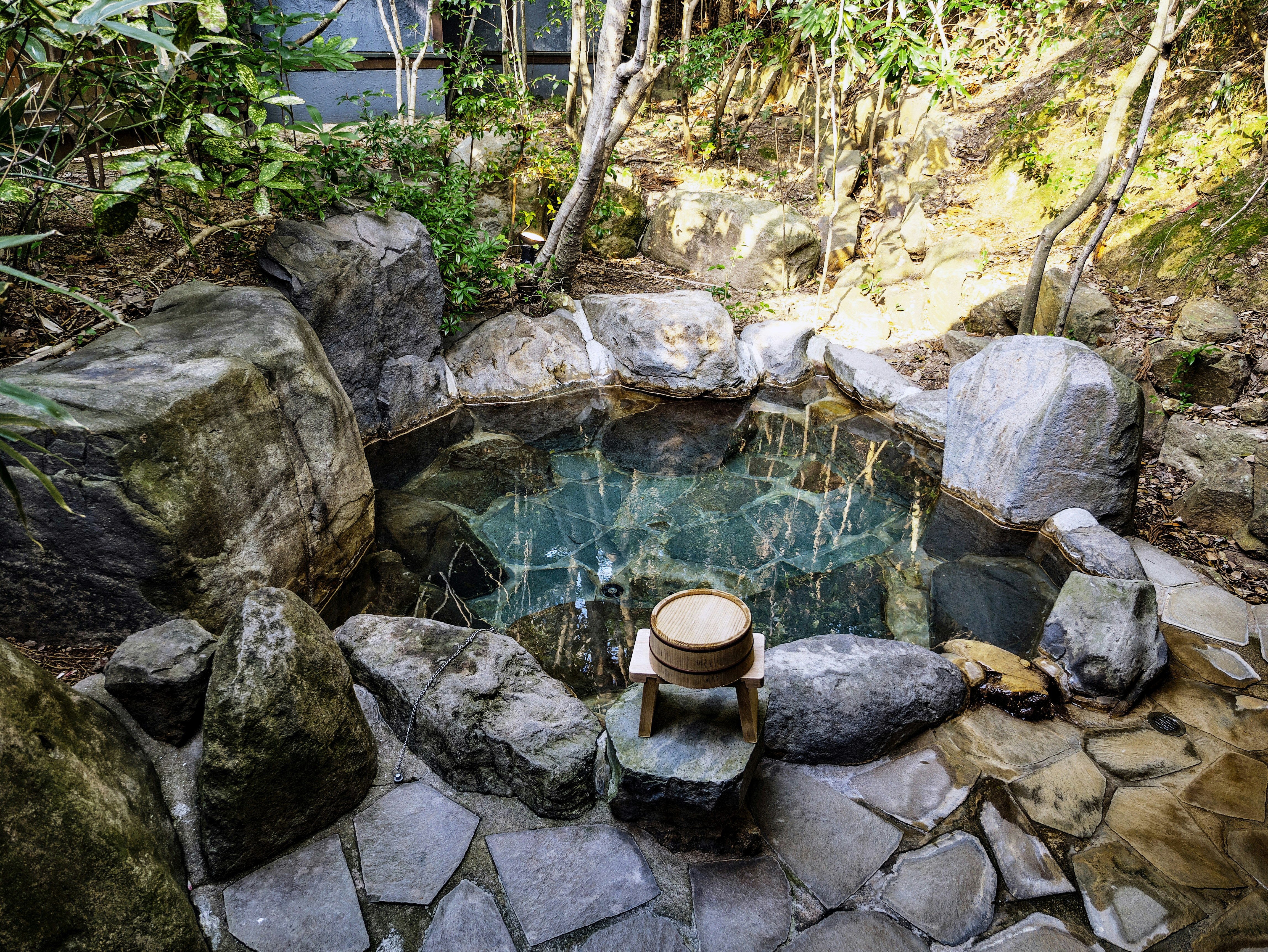岩に囲まれた露天風呂の湯船と木桶