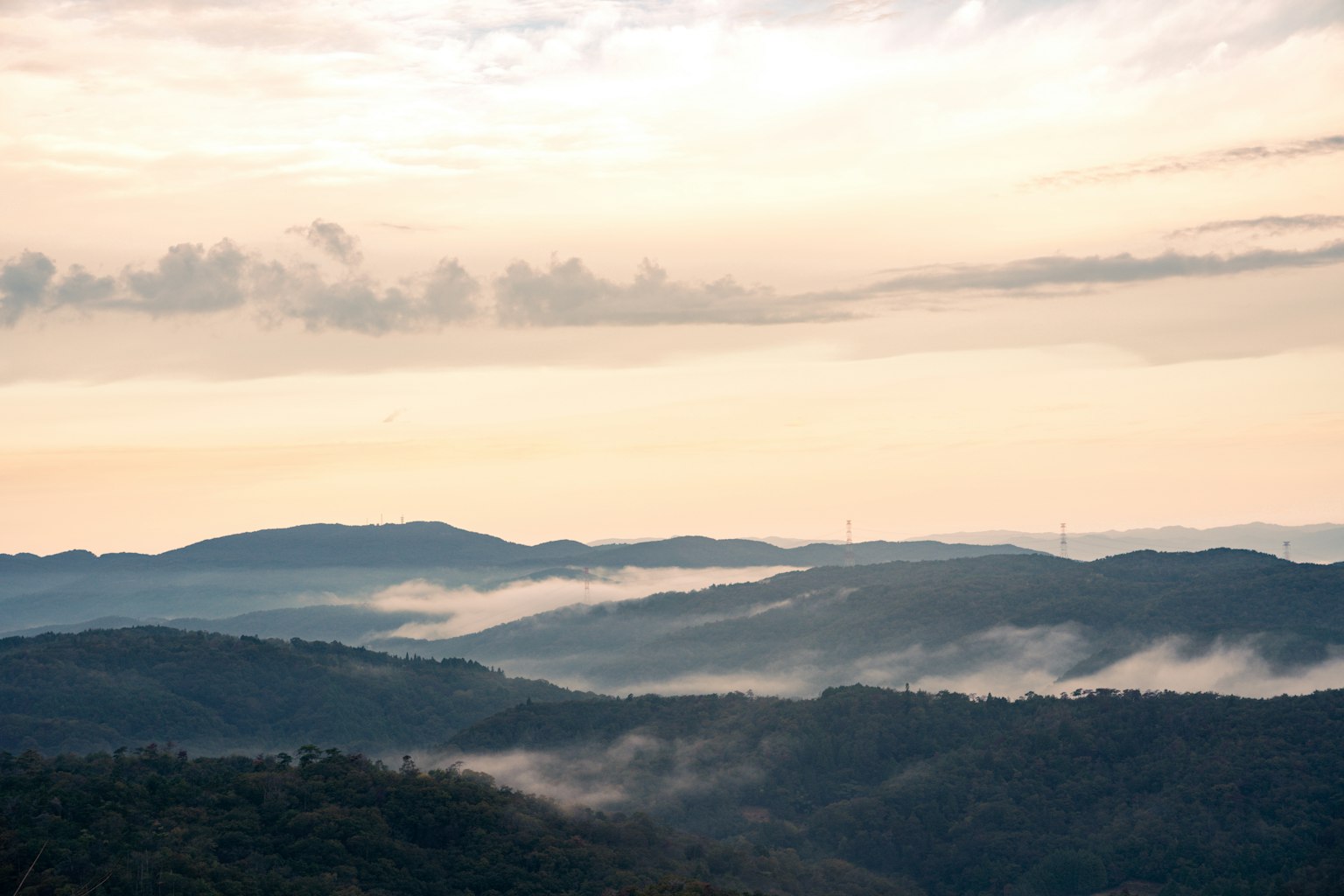 Paisaje montañoso con niebla y nubes al atardecer