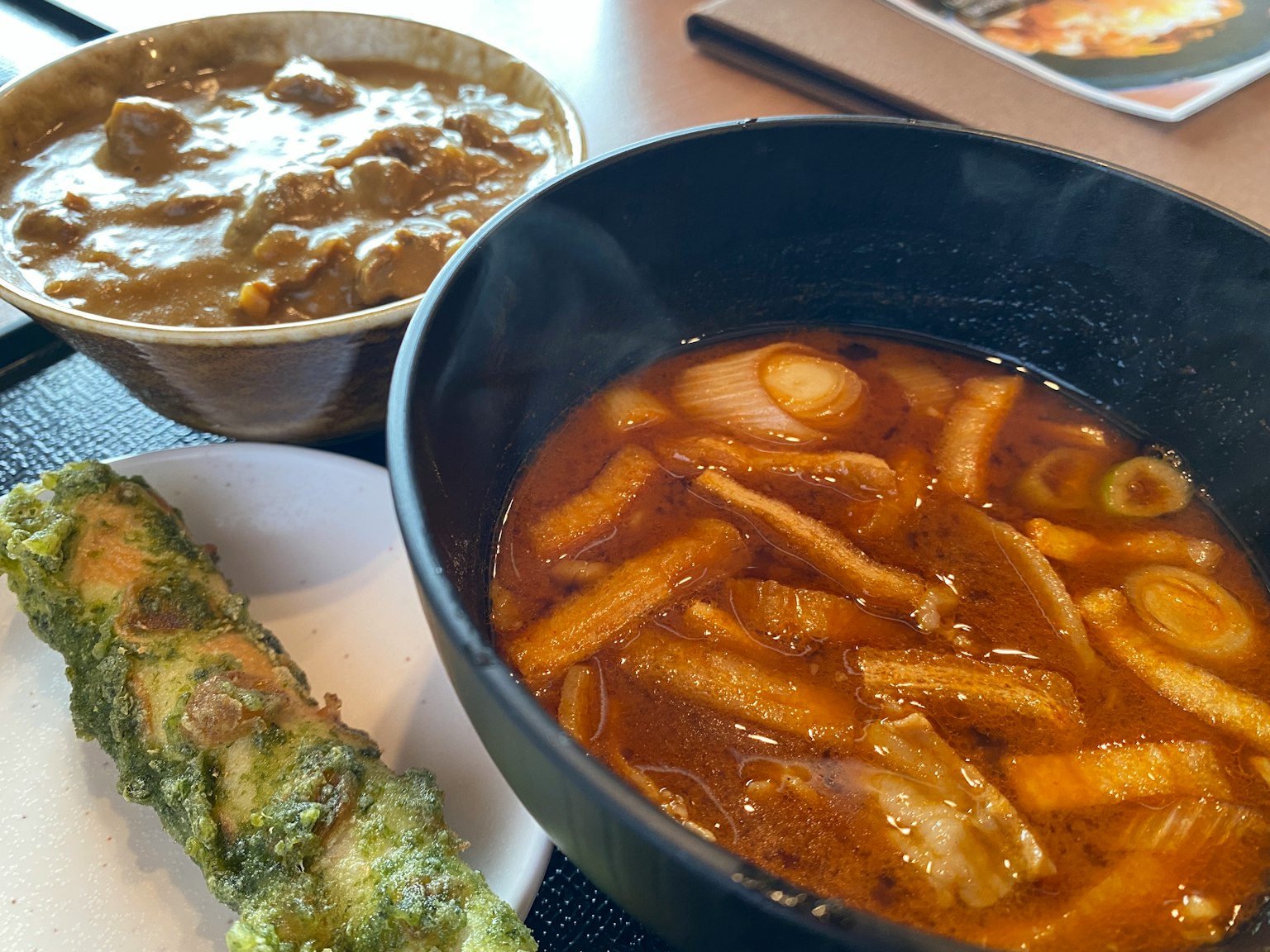 Un piatto con curry, zuppa di noodle e un alimento fritto