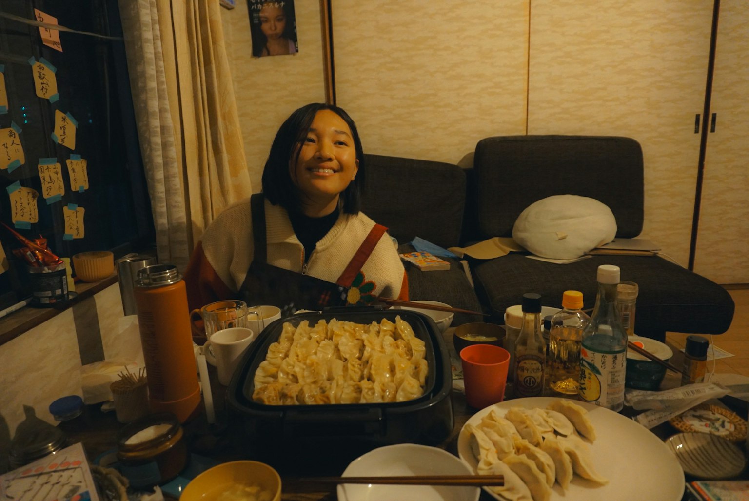 一位微笑的女性坐在桌子旁，周围有饺子