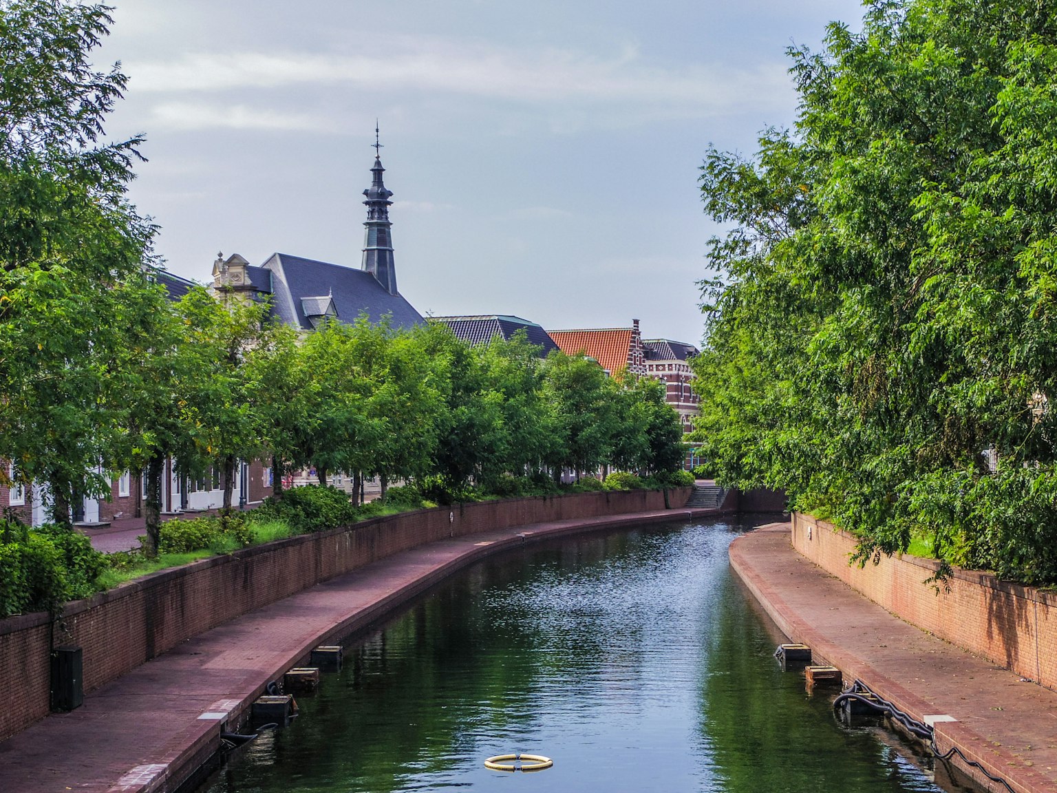 Malersicher Blick auf einen ruhigen Kanal mit üppigem Grün und historischen Gebäuden