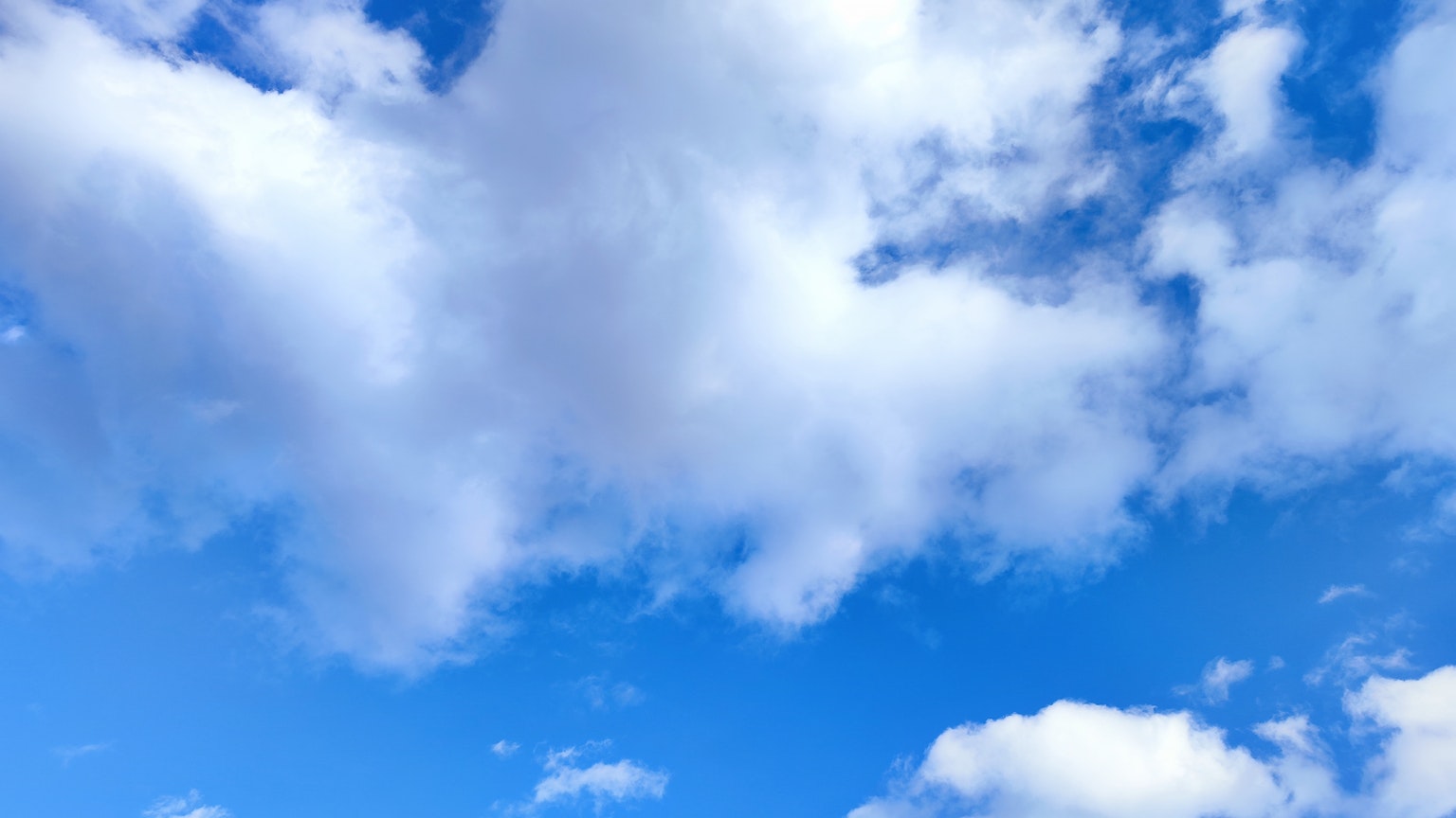 A scene of white clouds floating in a blue sky
