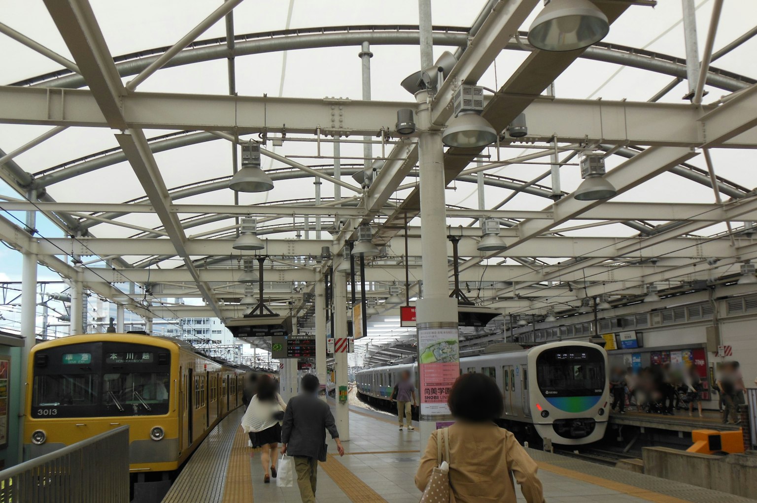 Interior stasiun kereta yang terang dengan orang-orang dan dua kereta terlihat