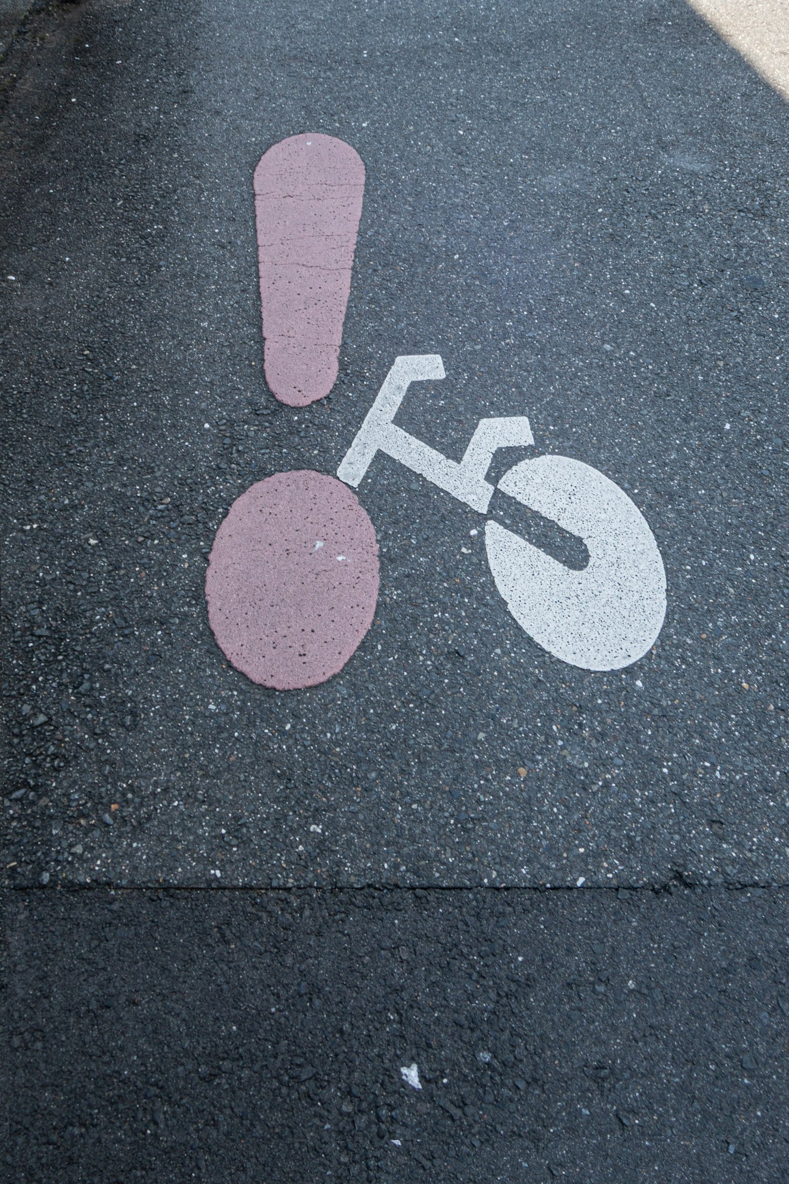 Un symbole de vélo avec un point d'exclamation peint sur un chemin pavé