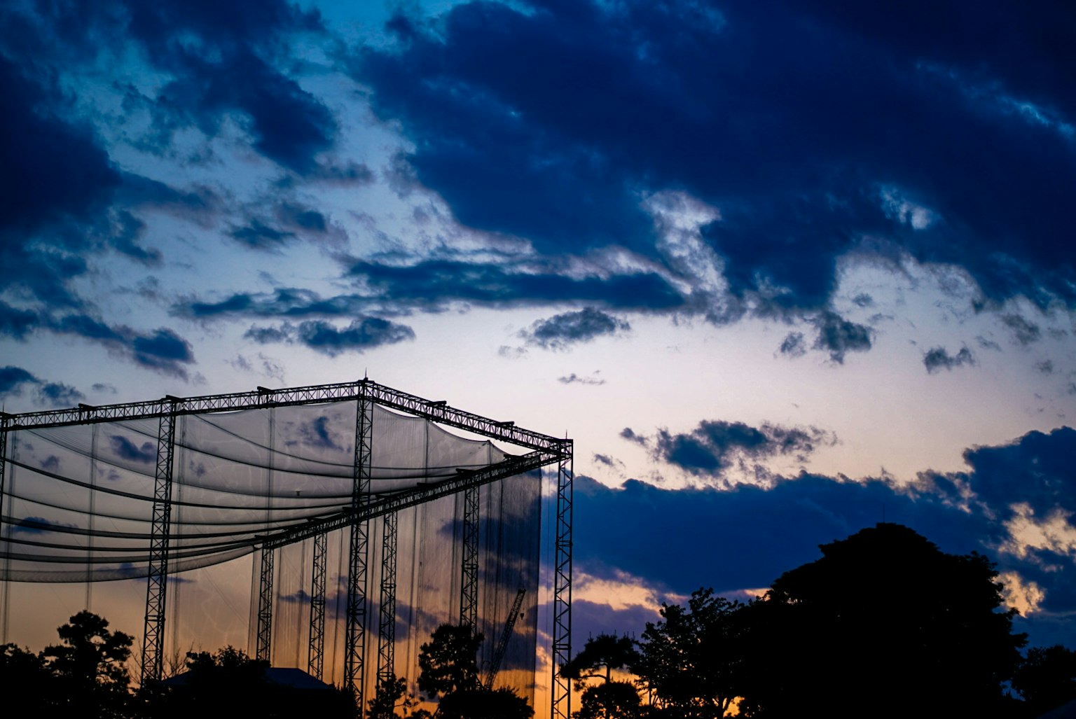 Silhouette di una rete di driving range contro un cielo al tramonto