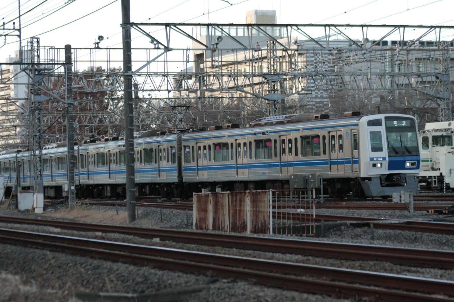 รถไฟที่มีแถบสีน้ำเงินวิ่งผ่านสภาพแวดล้อมทางรถไฟในเมือง