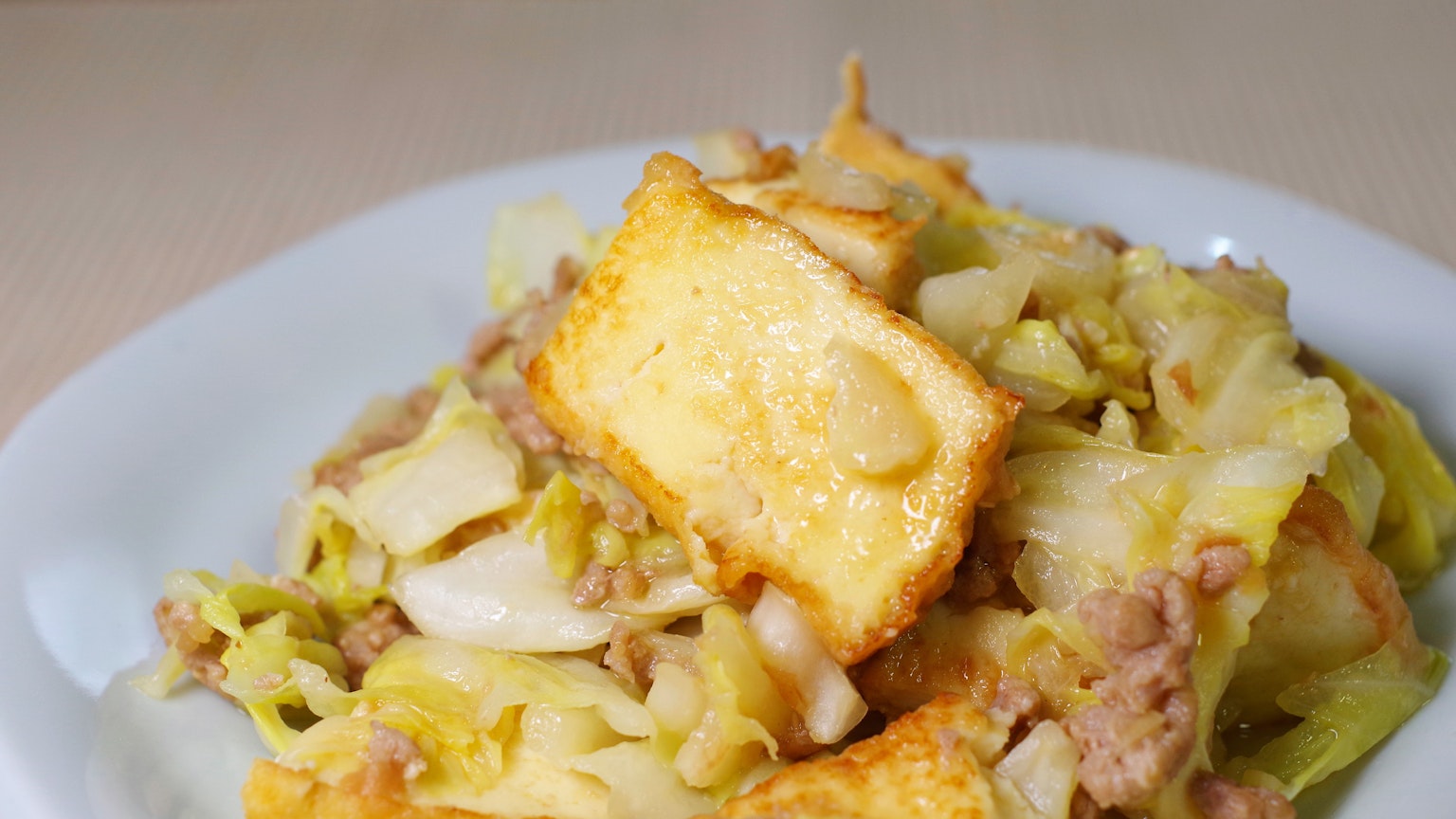 Gebratener Kohl und Schweinefleisch mit frittiertem Tofu auf einem Teller