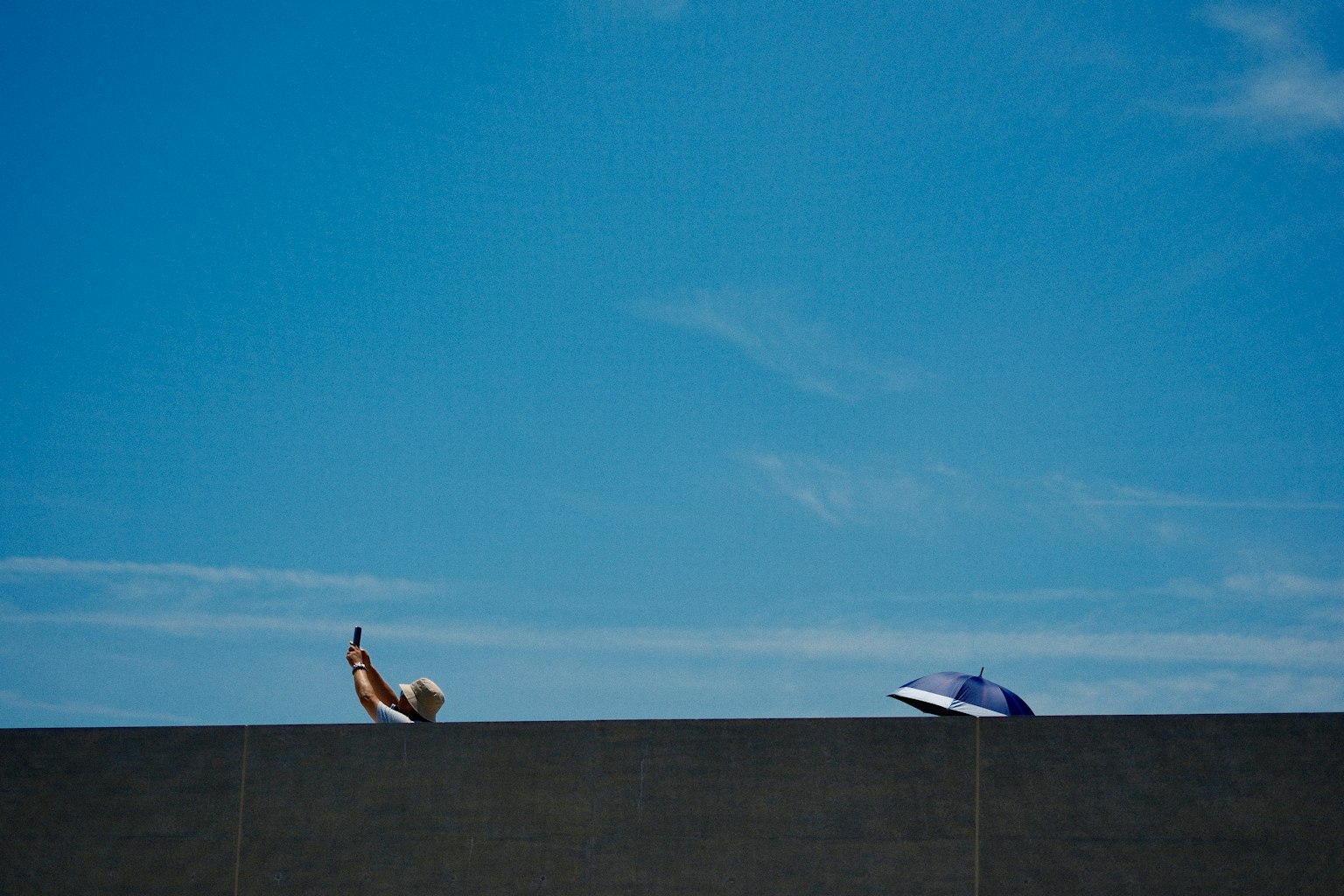 Eine Person sitzt auf einem Liegestuhl und ein Schwimmring unter einem klaren blauen Himmel