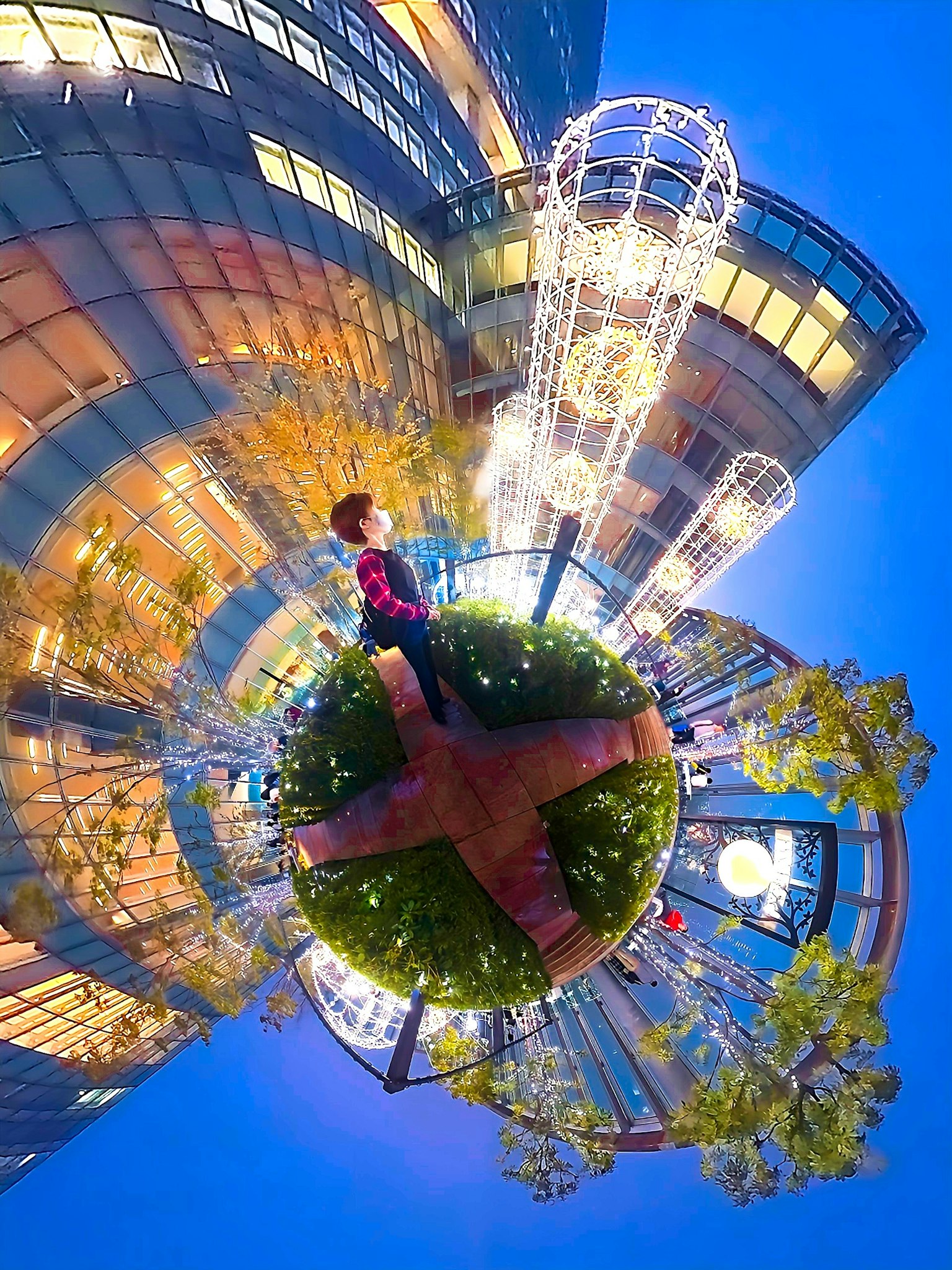 Una persona che tiene un piccolo globo con uno sfondo di un paesaggio urbano illuminato da luci sotto un cielo blu