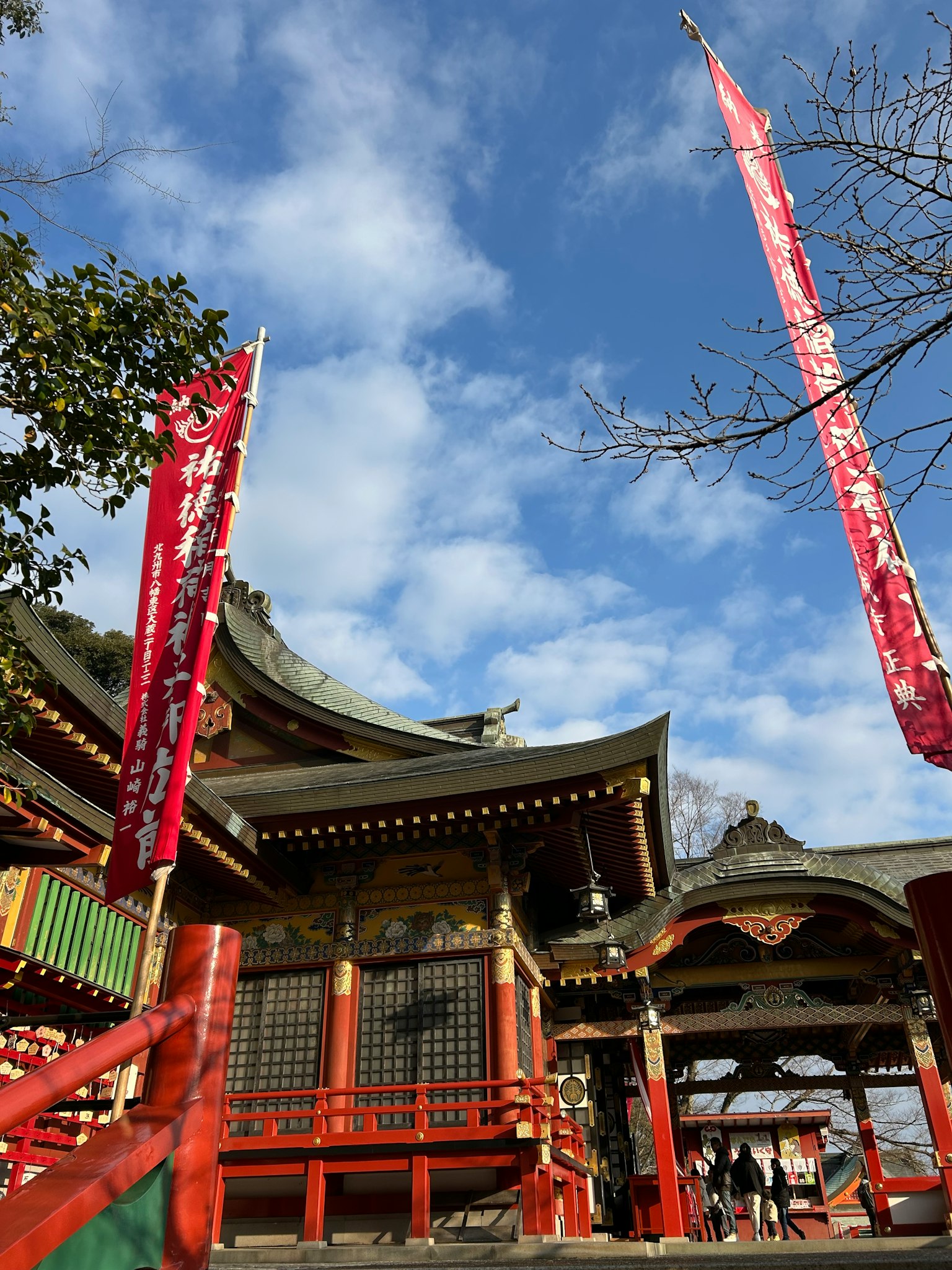 Traditional Japanese shrine building under blue sky with red banners
