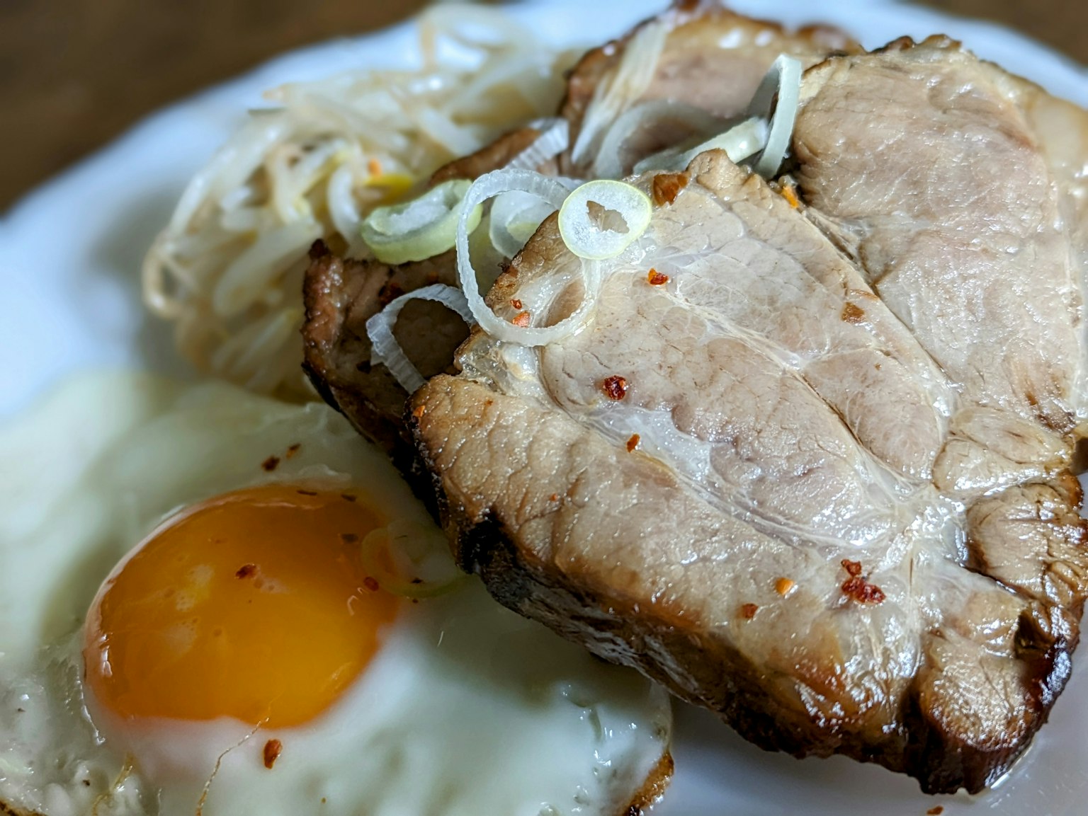 Teller mit Scheiben von Schweinefleisch und einem Spiegelei