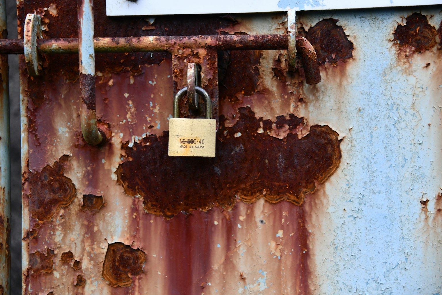 Puerta de metal oxidada con un candado y un marco de hierro envejecido