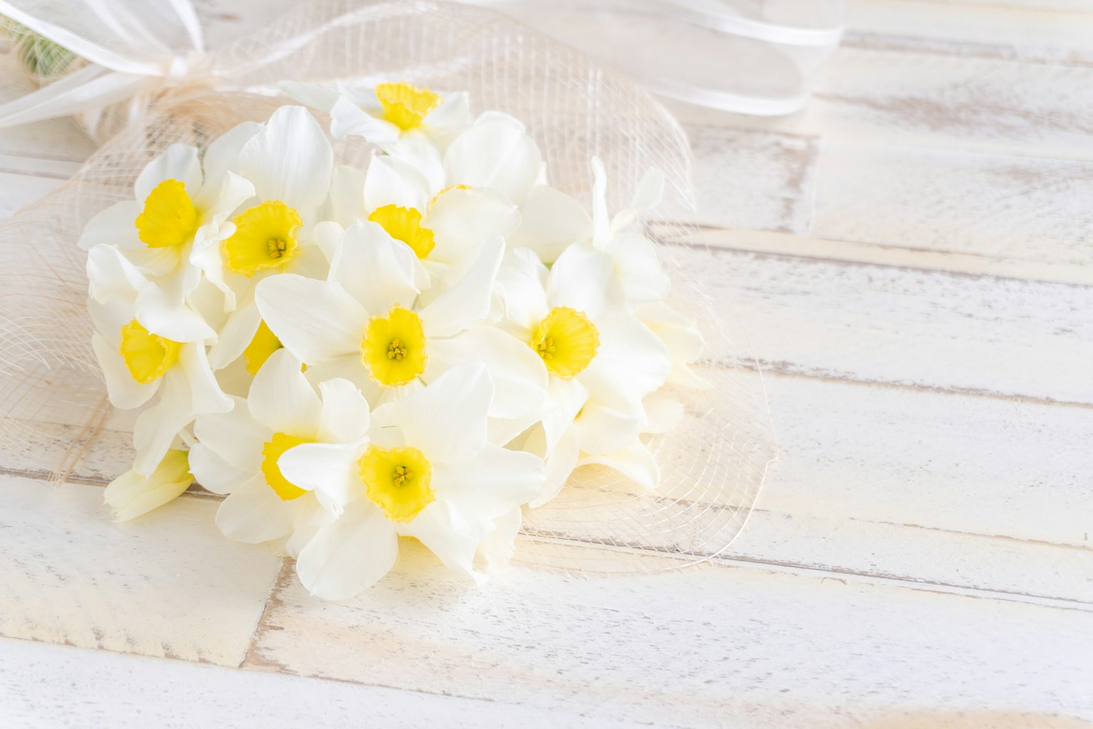 Un ramo de flores blancas con centros amarillos sobre una mesa de madera