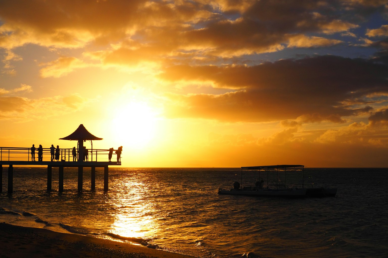 Scène de plage magnifique avec coucher de soleil sur l'océan personnes debout sur un quai