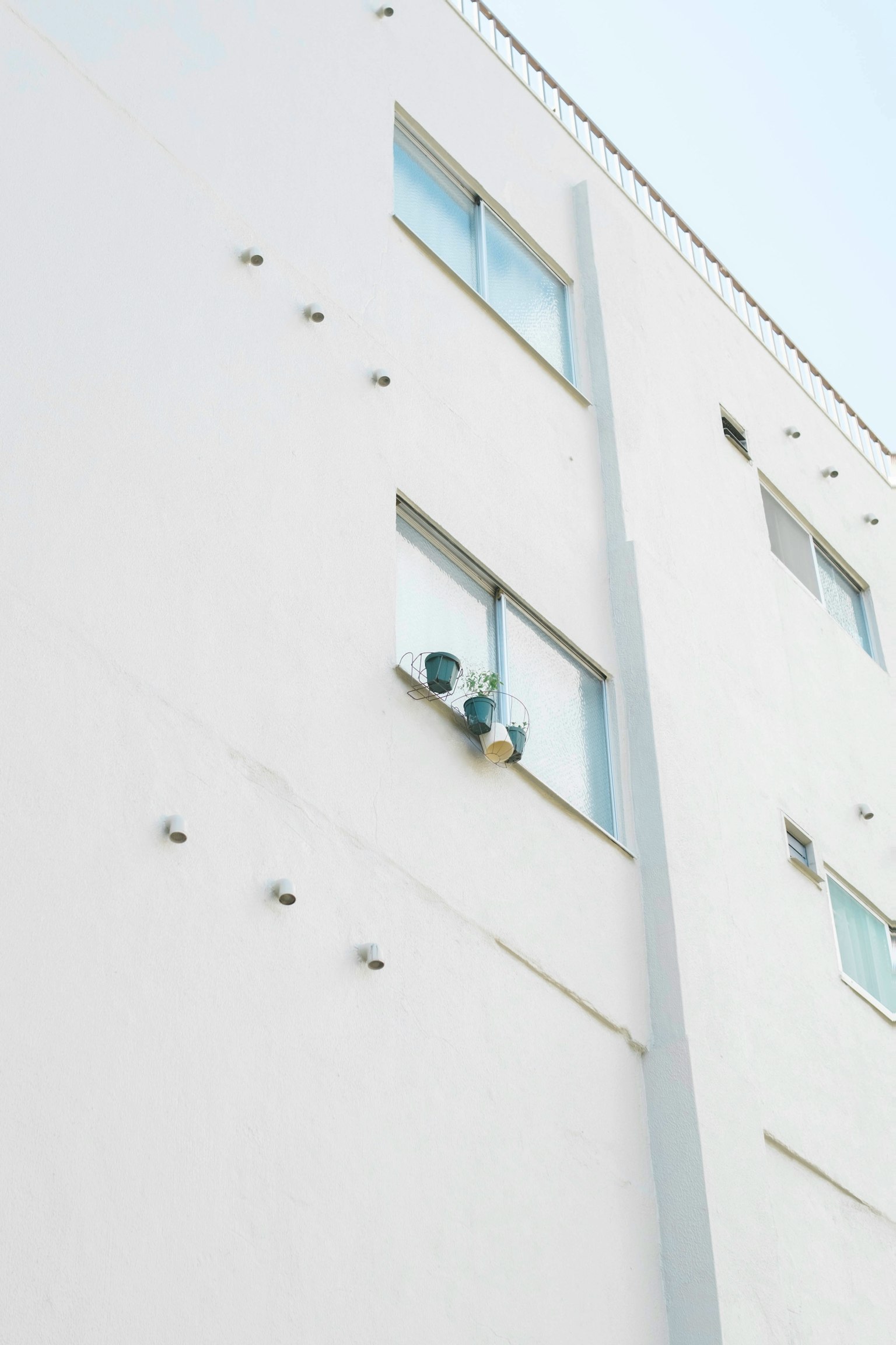 Air conditioning units mounted on a white building wall with windows