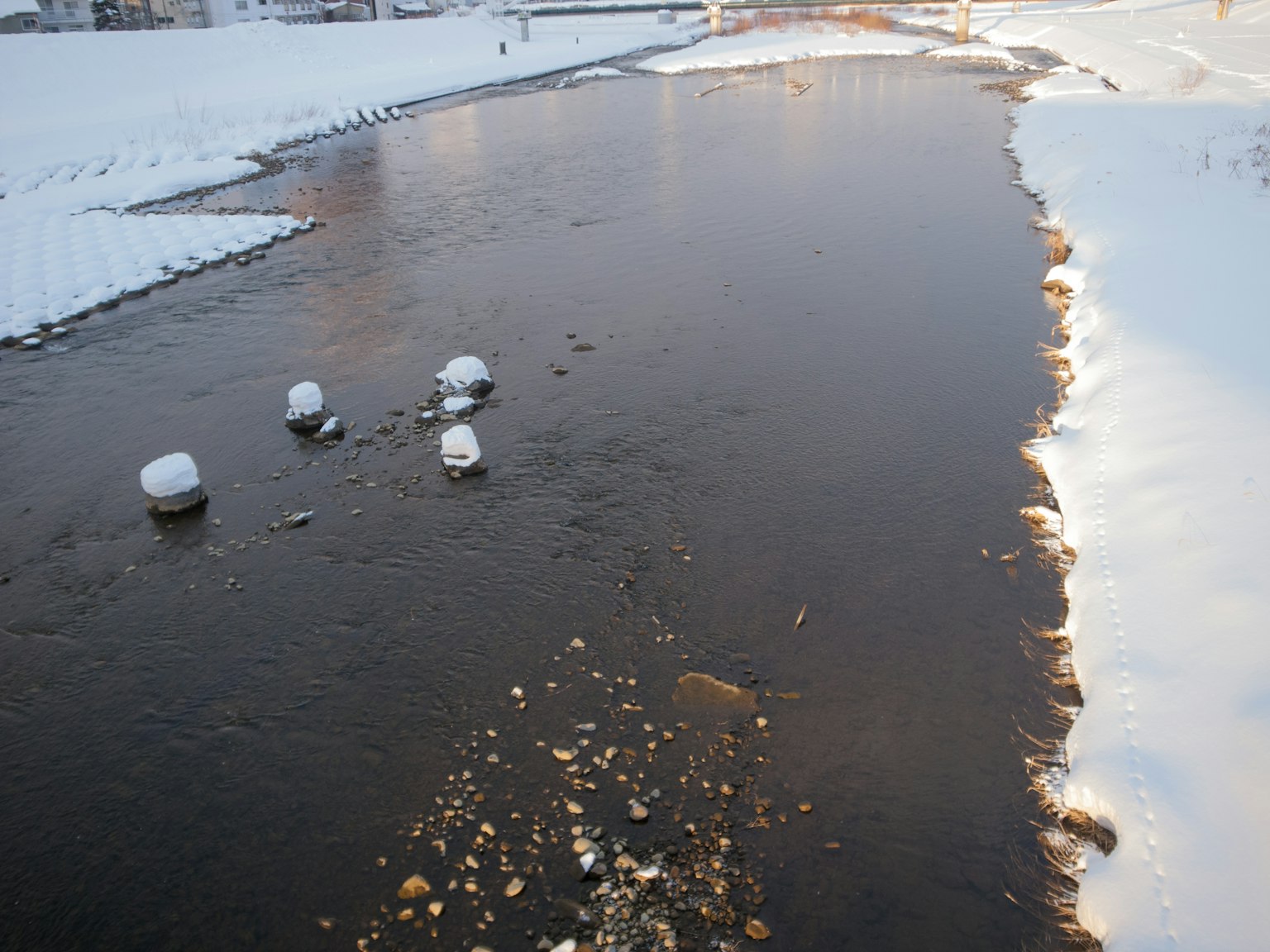 Winterszene eines Flusses mit schneebedeckten Ufern und schwimmenden Eisstücken