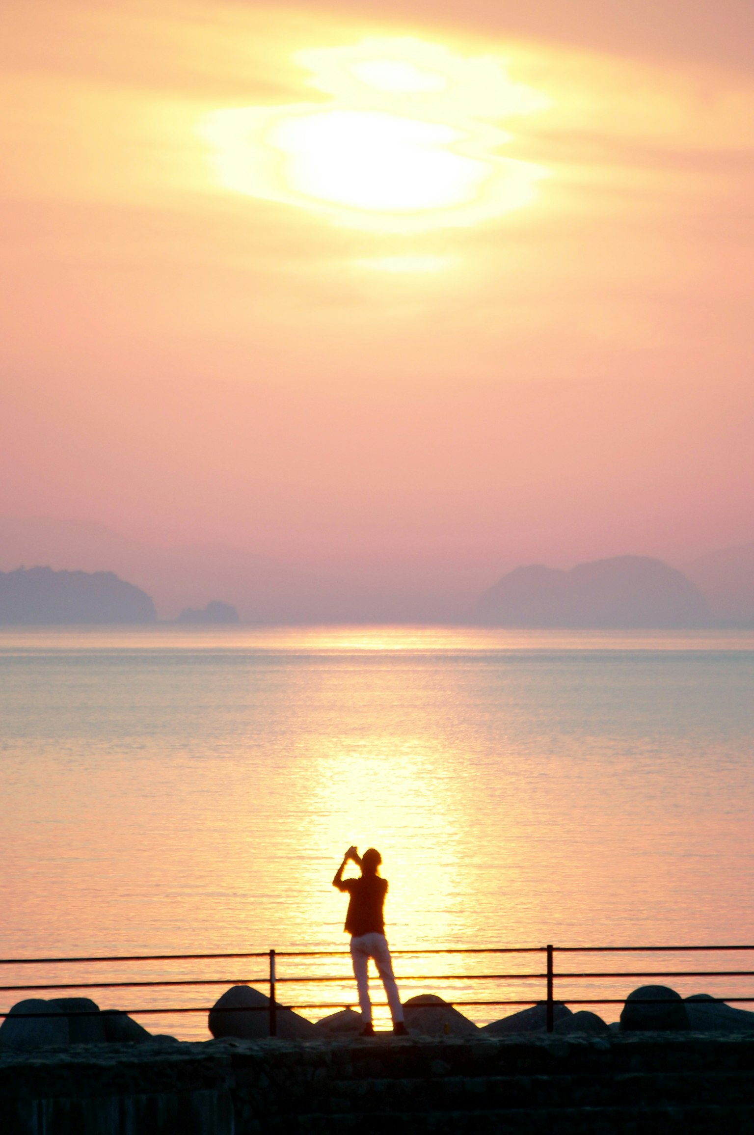 夕阳背景下凝视大海的人影