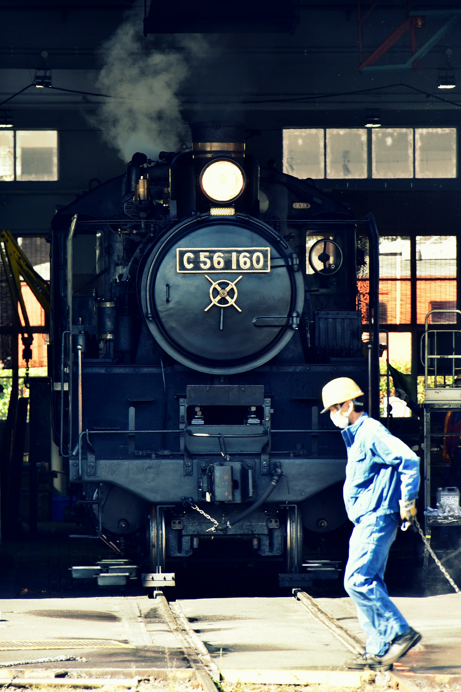 Lokomotif uap C56160 di bengkel dengan pekerja yang berjalan