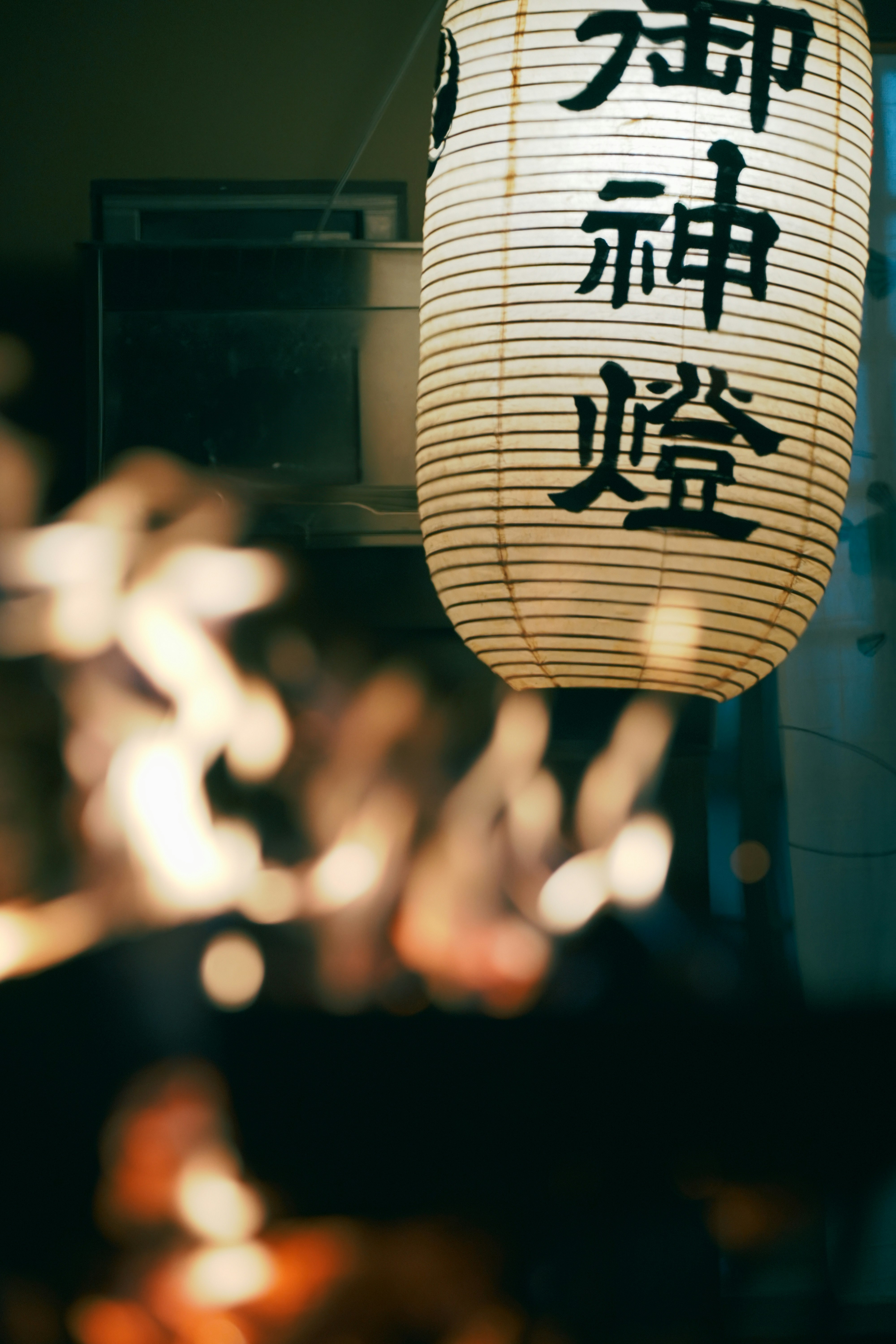 Lantern with text from Kurama-yama and warm lights along a shrine approach