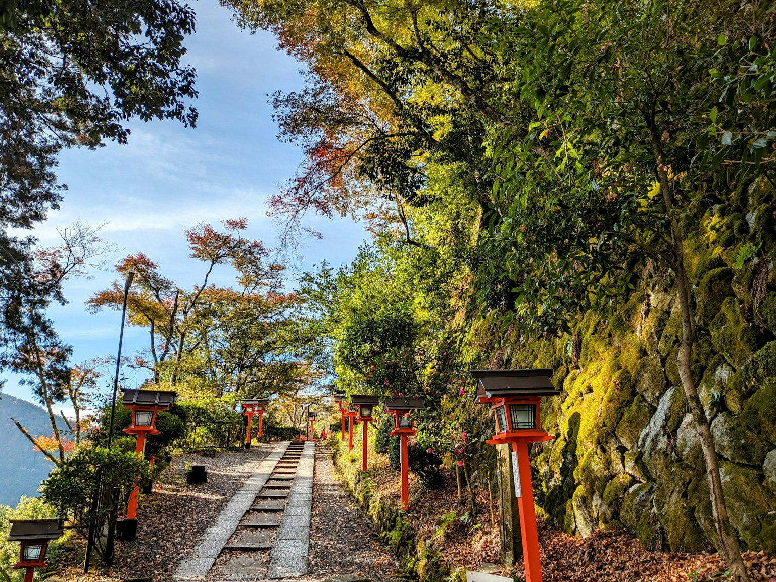 A scenic path lined with red lanterns and vibrant autumn foliage