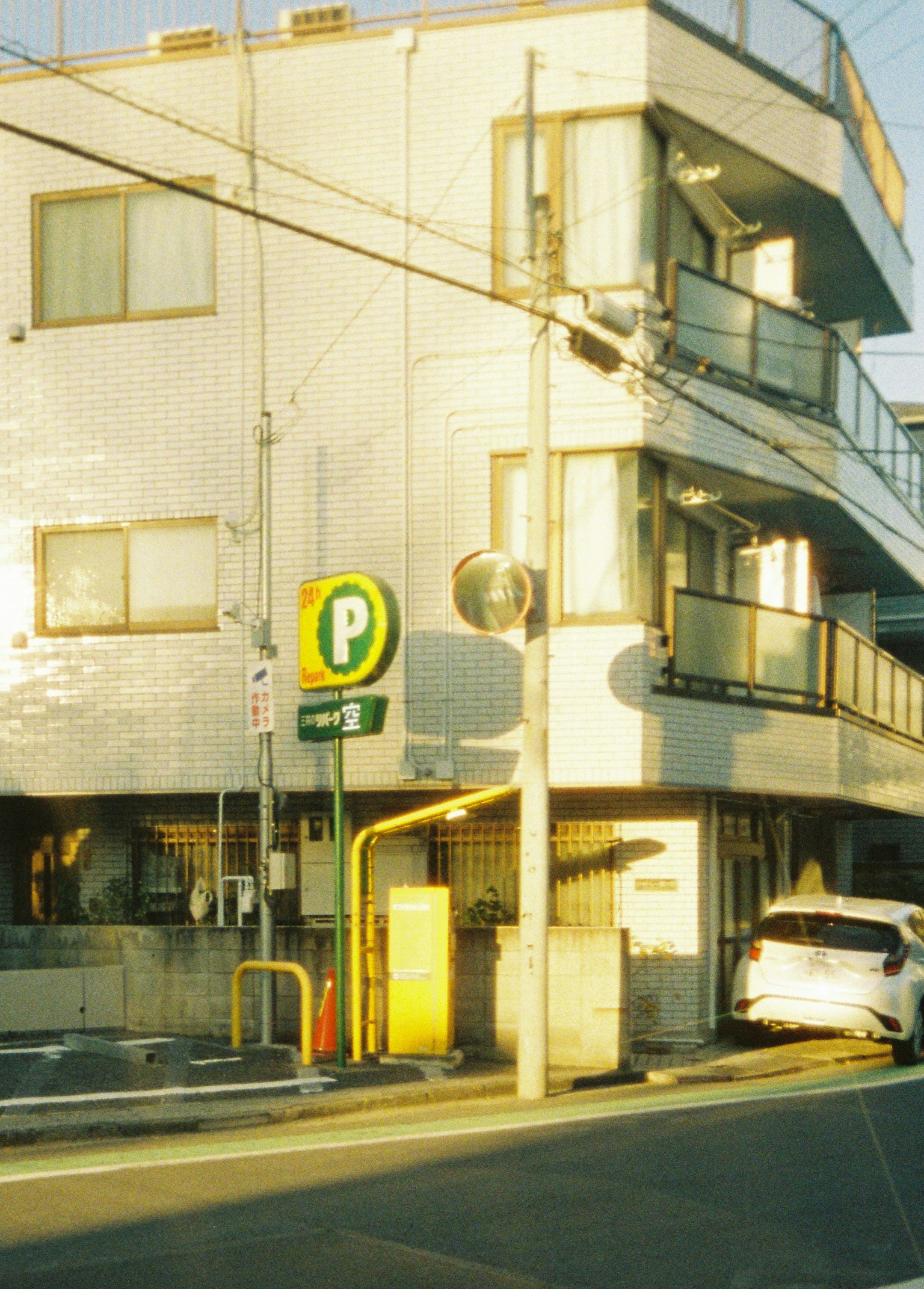 Vista de una esquina de la calle con un edificio de fachada blanca y un letrero de estacionamiento