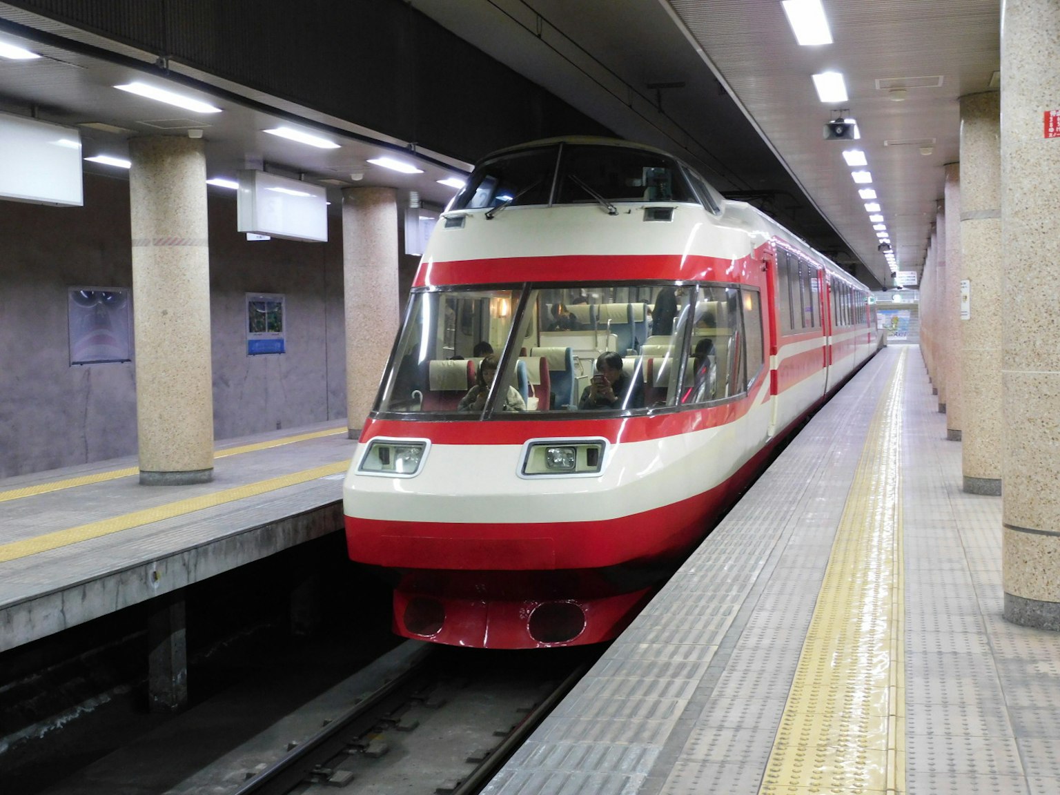 Kereta merah dan putih di platform kereta bawah tanah